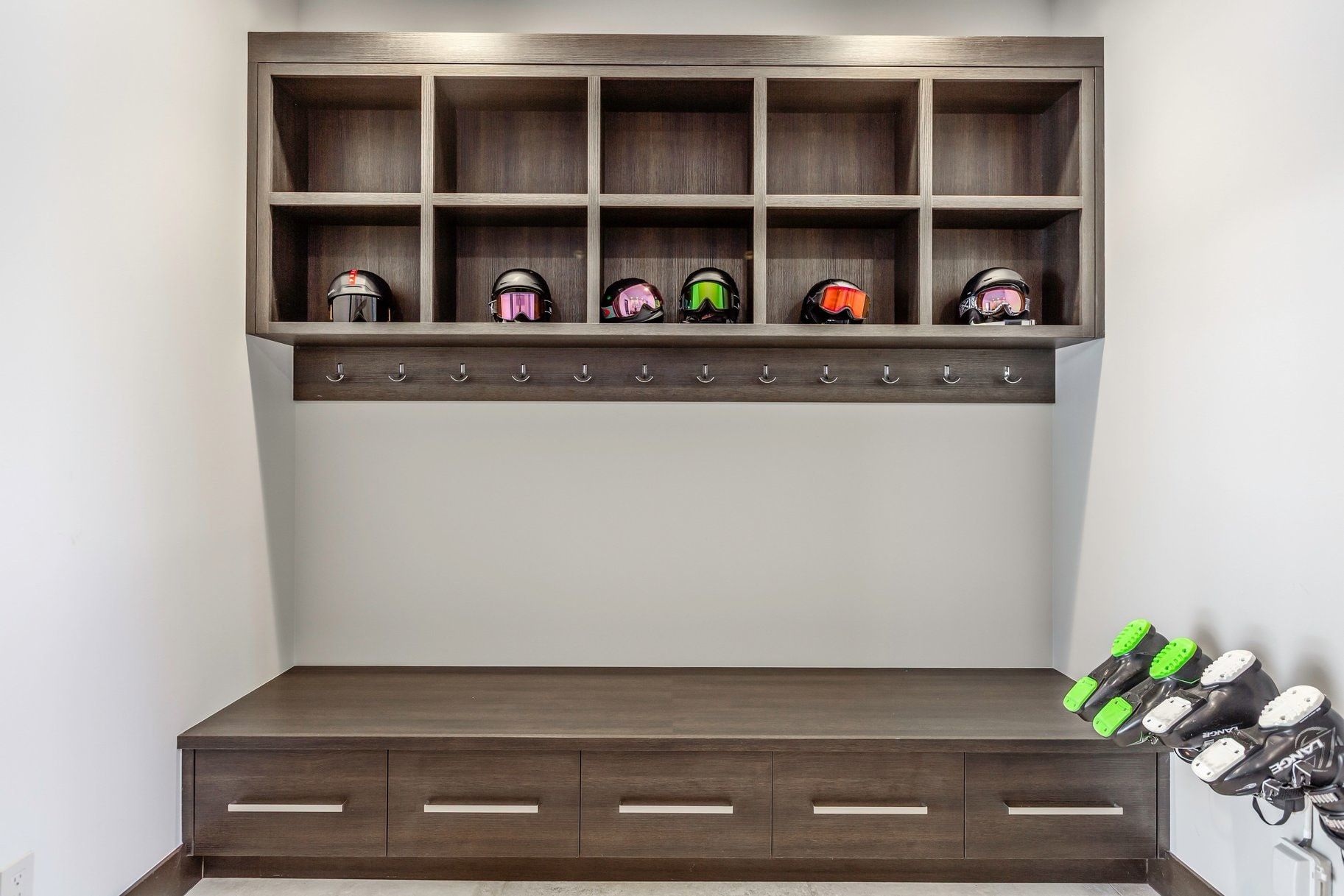 Built-in wood-finish cabinetry featuring open shelving, integrated coat hooks, and storage drawers