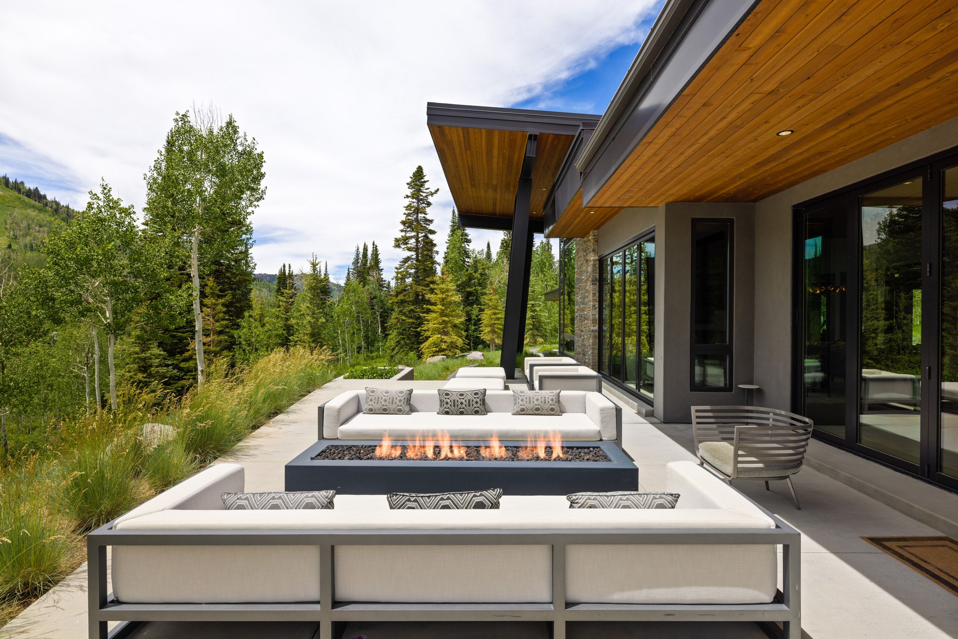 Expansive outdoor patio featuring a built-in fire pit, concrete hardscaping, and a wood-paneled soffit