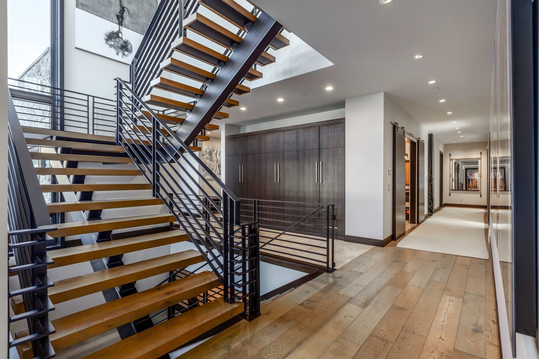 Open-riser staircase featuring wood treads and black metal railings