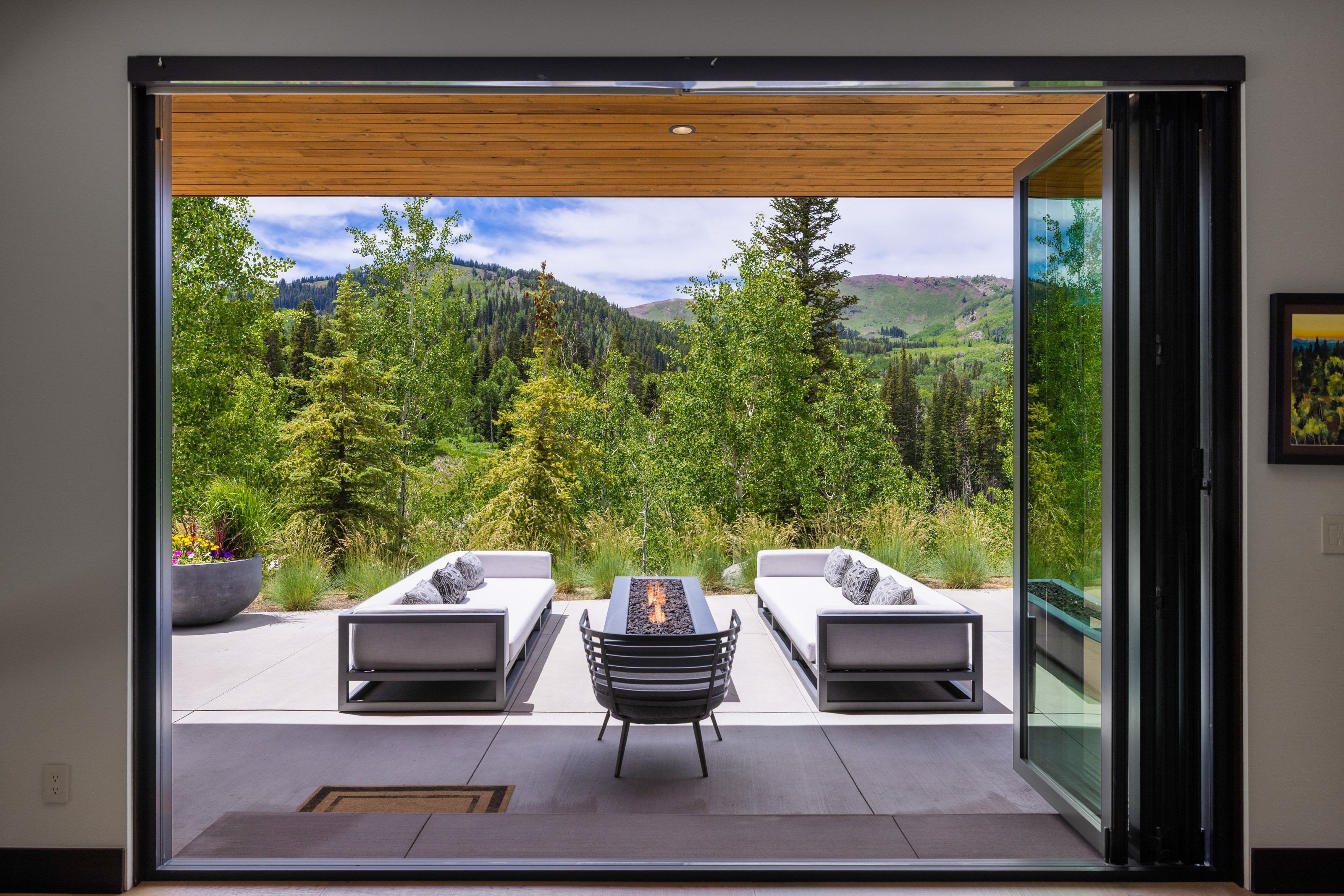 Expansive outdoor patio featuring large format pavers, a fire pit, and a wooded mountain backdrop
