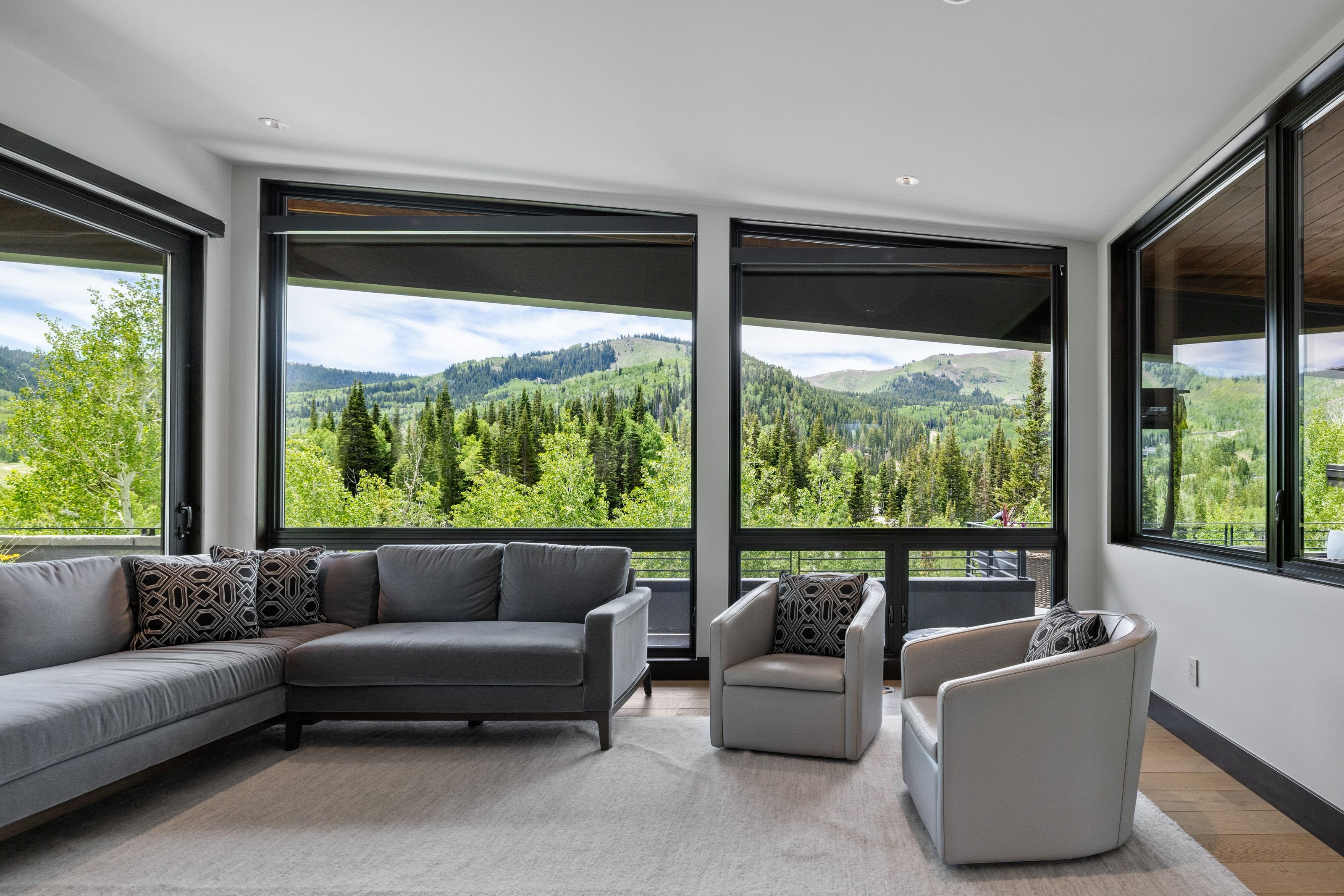 Expansive window walls frame a mountainous landscape with mature trees