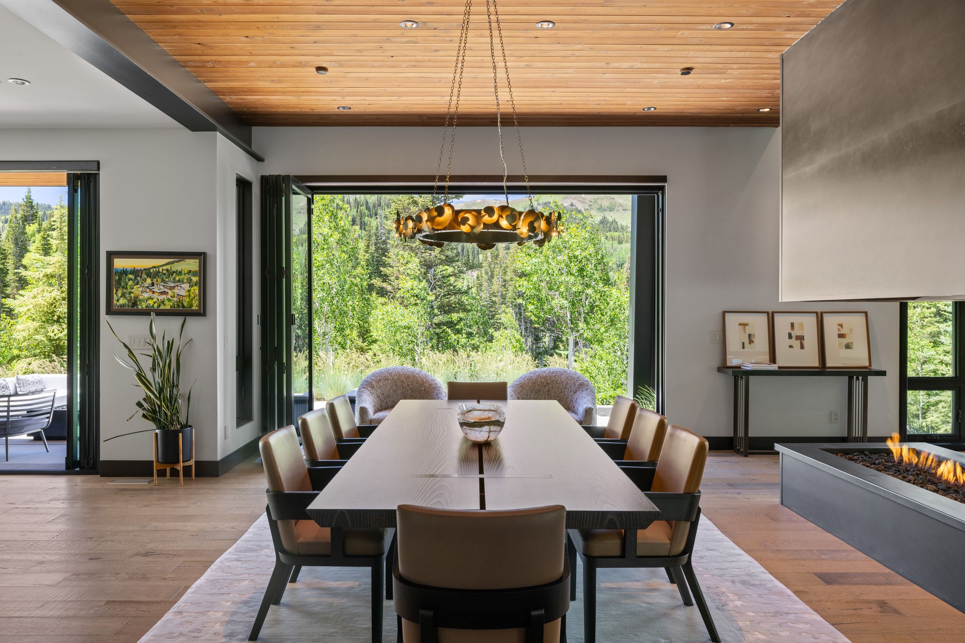 Dining area with wood-finish flooring, a wood-paneled ceiling, and a linear gas fireplace