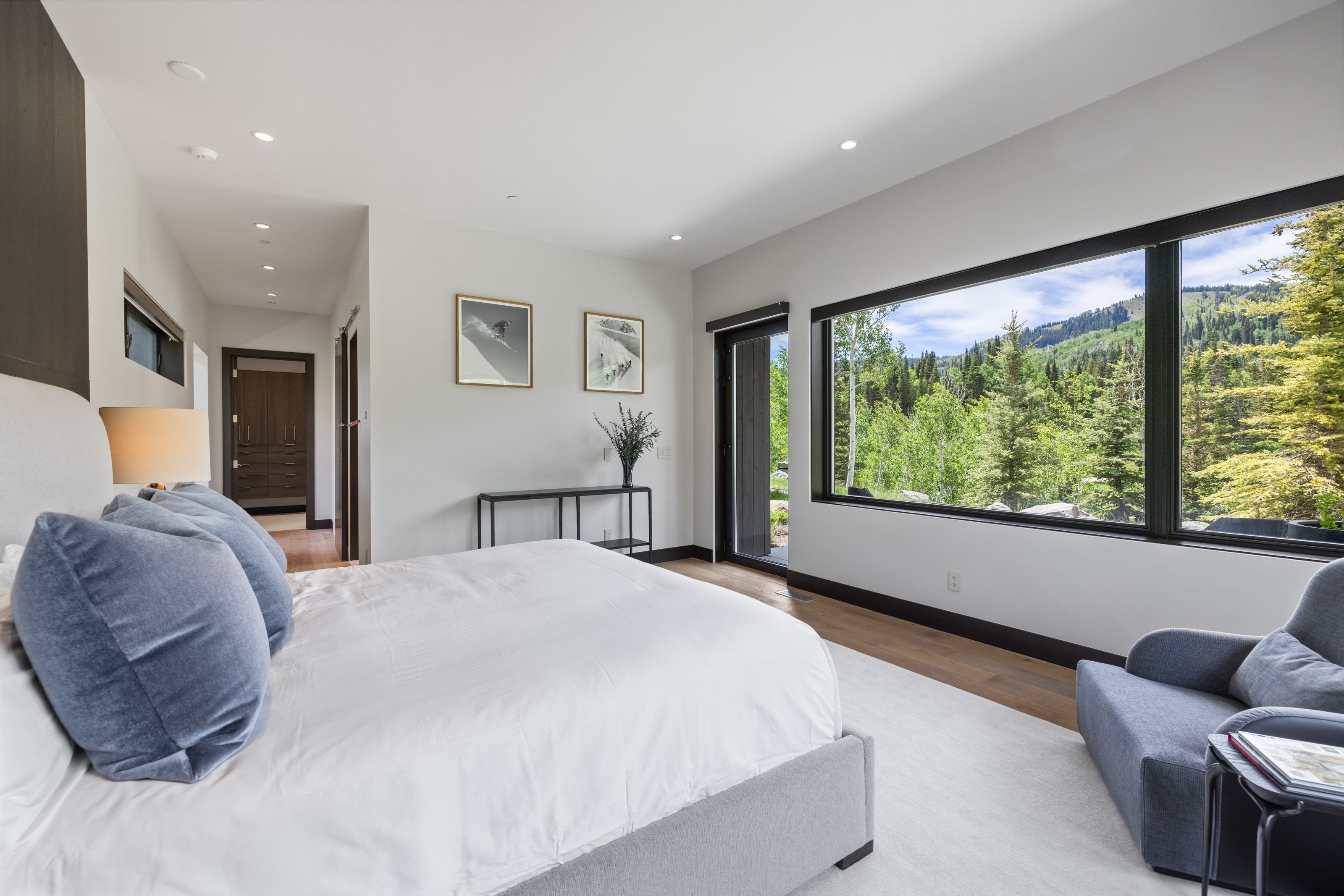 Expansive bedroom featuring a large picture window, a sliding glass door, recessed lighting, wood-finish flooring, and a textured area rug