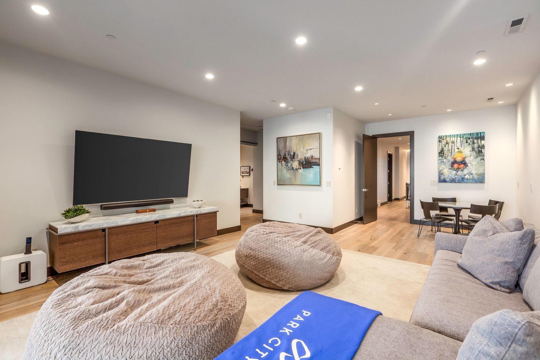 Open-concept living space featuring wood-finish flooring, recessed lighting, and a contemporary media console with a stone top