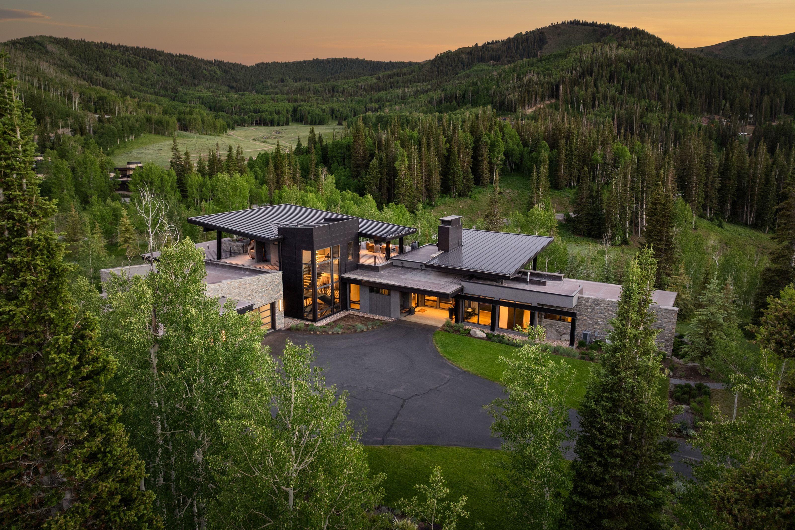 Modern architectural residence featuring a dark metal roof and stone facade