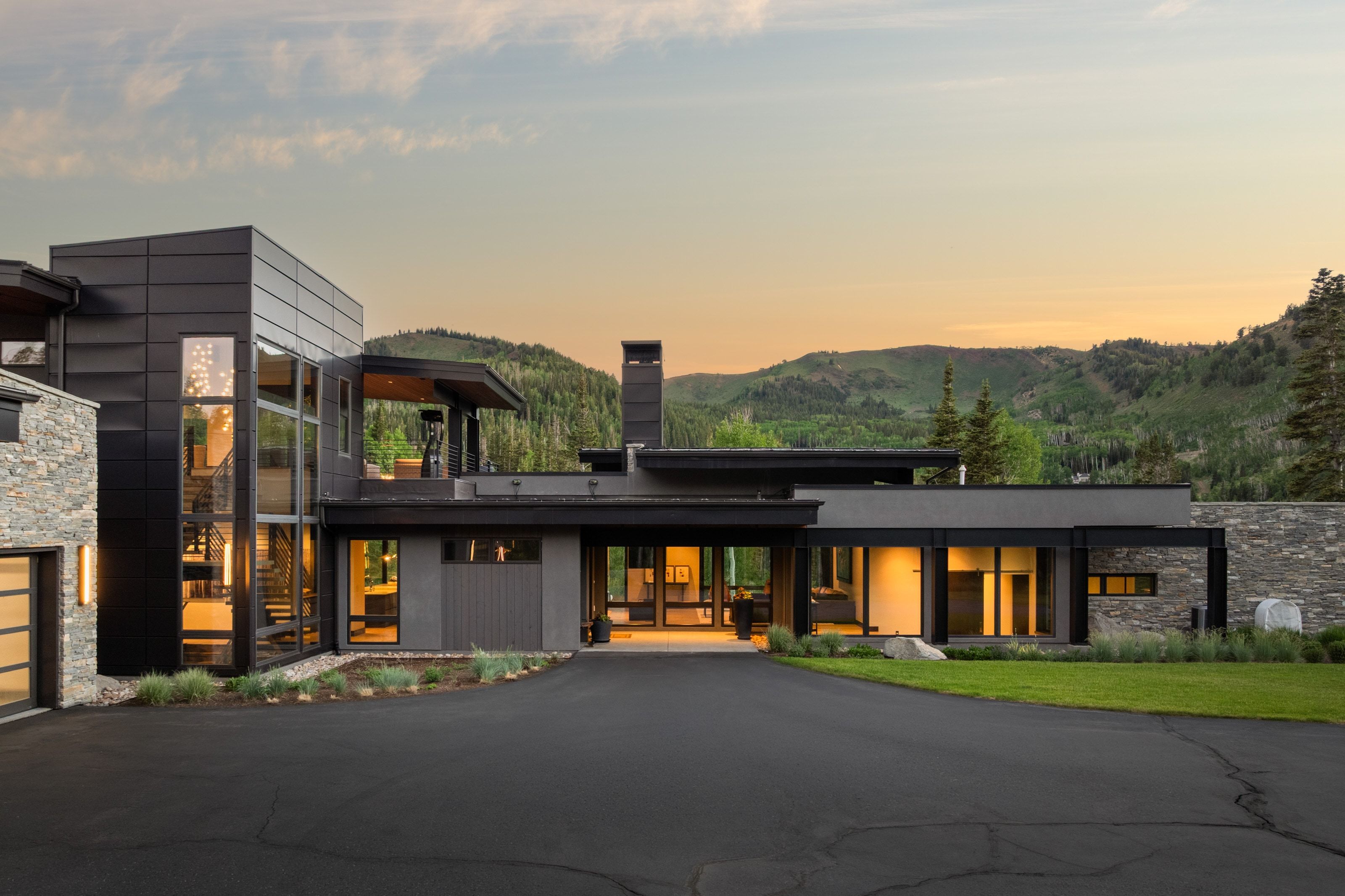 Modern architectural residence featuring extensive glass facades, a flat roofline, and a paved driveway