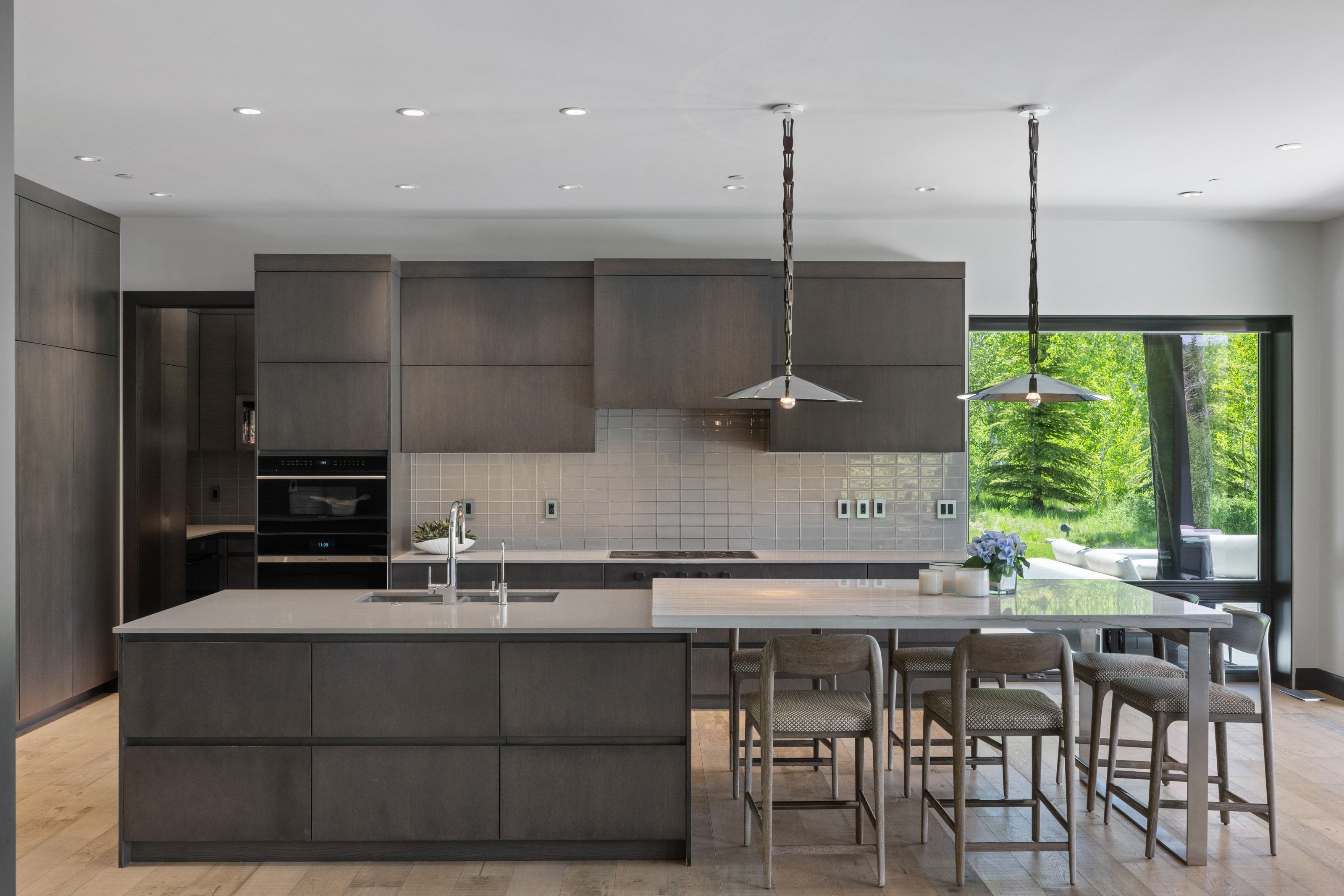 Modern kitchen featuring dark wood-finish cabinetry, a large center island with integrated sink, and an extended breakfast bar