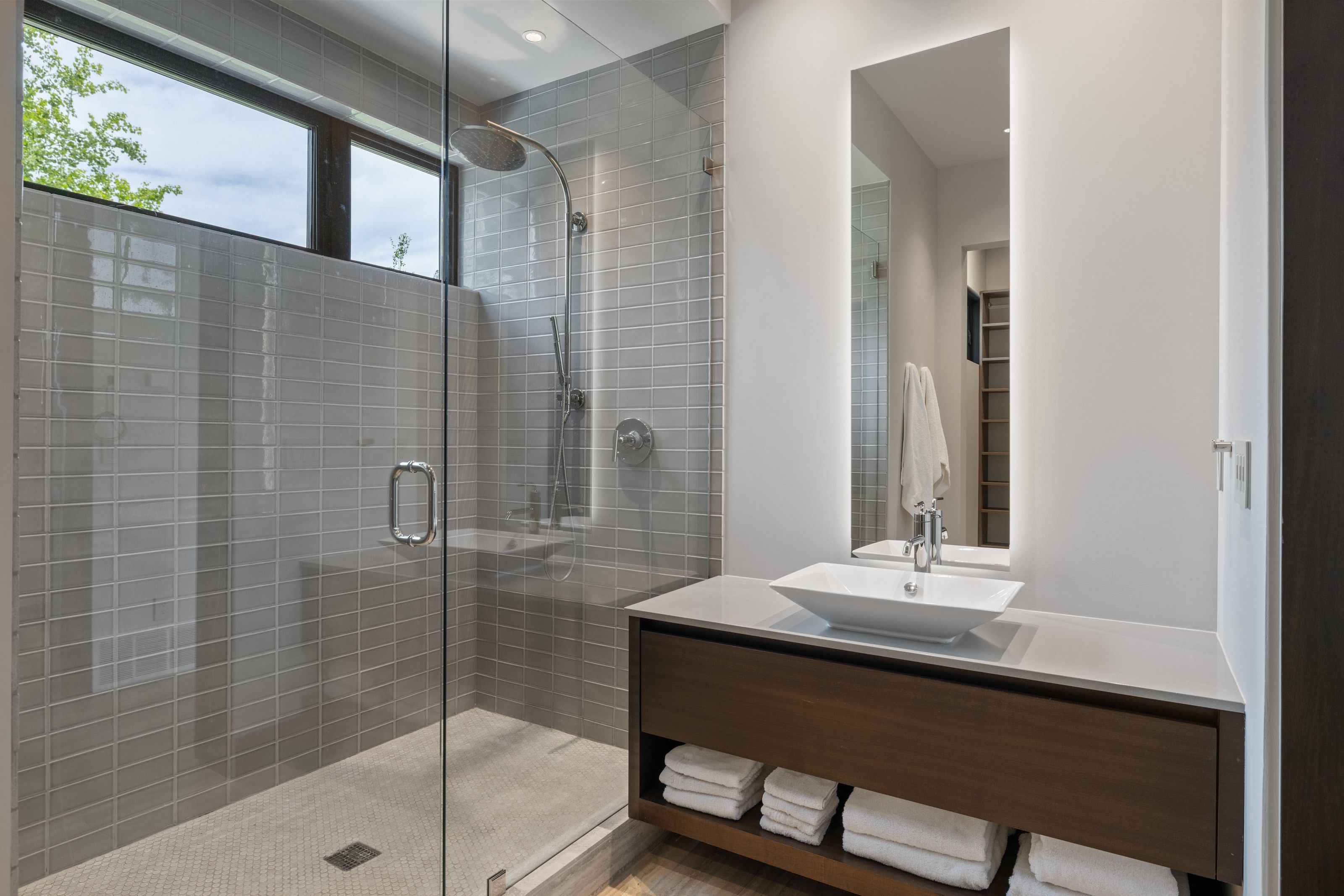 Contemporary bathroom featuring a spacious glass-enclosed shower with gray subway tile surround and a rain showerhead