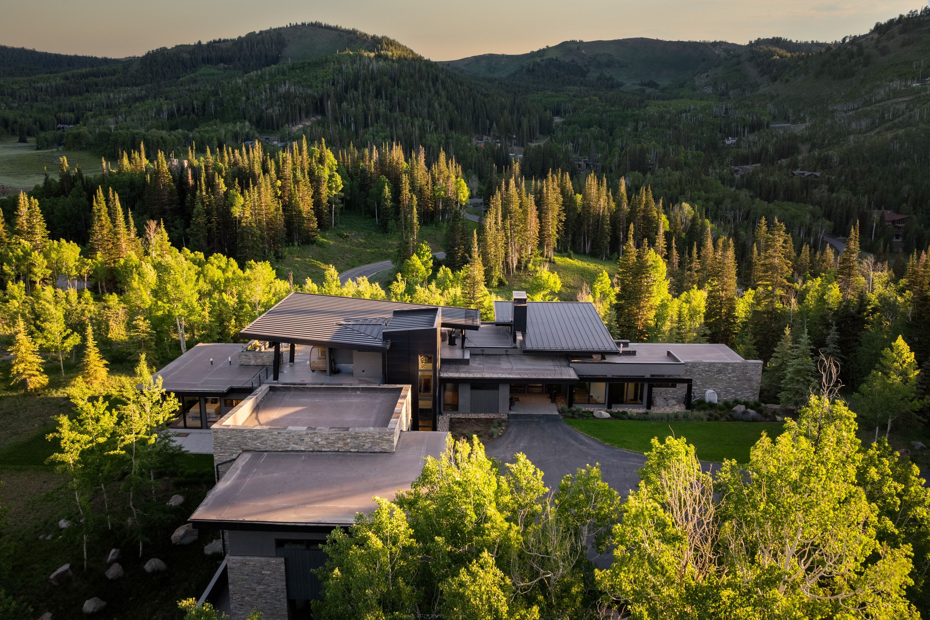 Modern mountain residence featuring a multi-level design, extensive flat rooflines, and stone accents