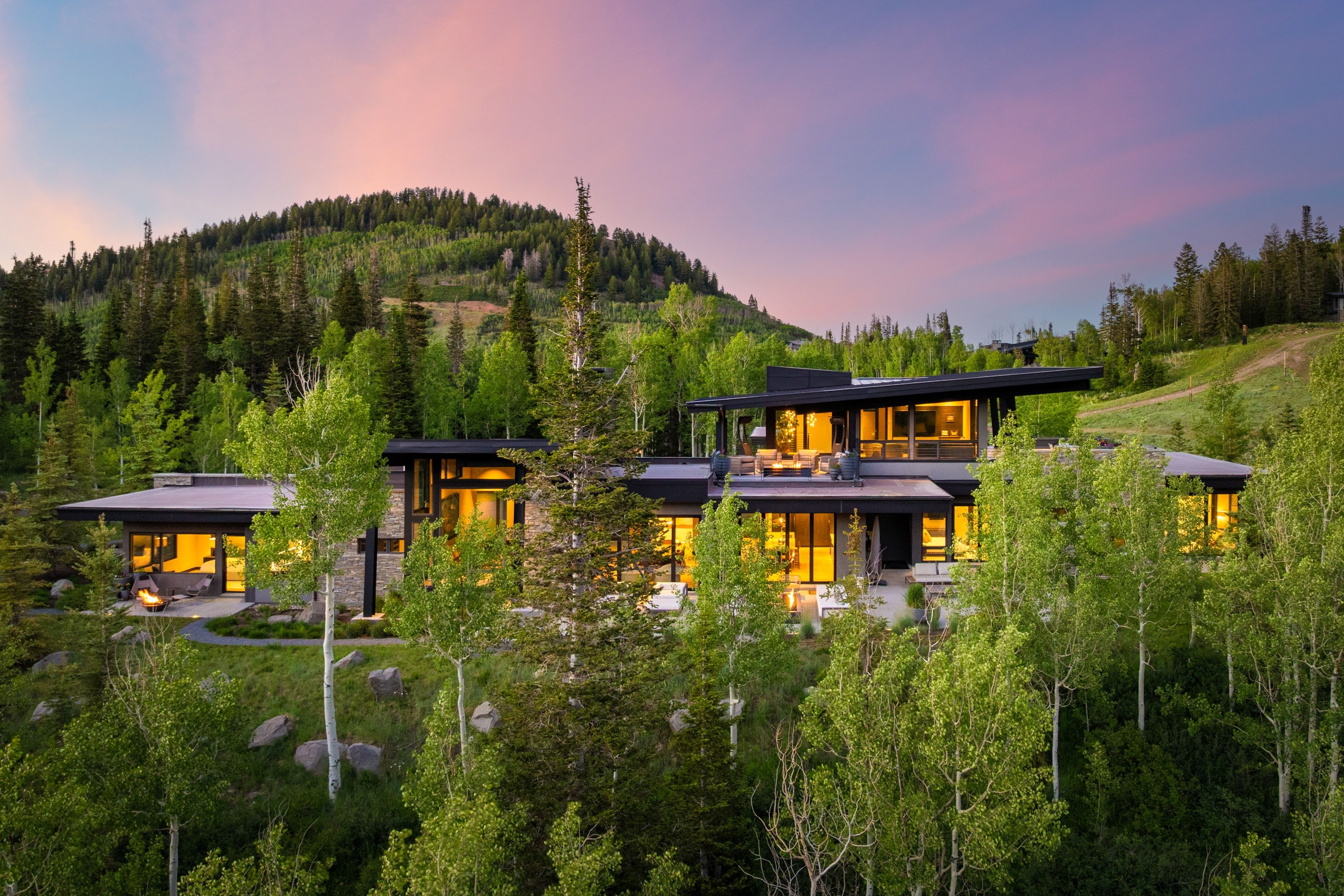 Modern architectural residence featuring extensive glazing, stone accents, and dark trim
