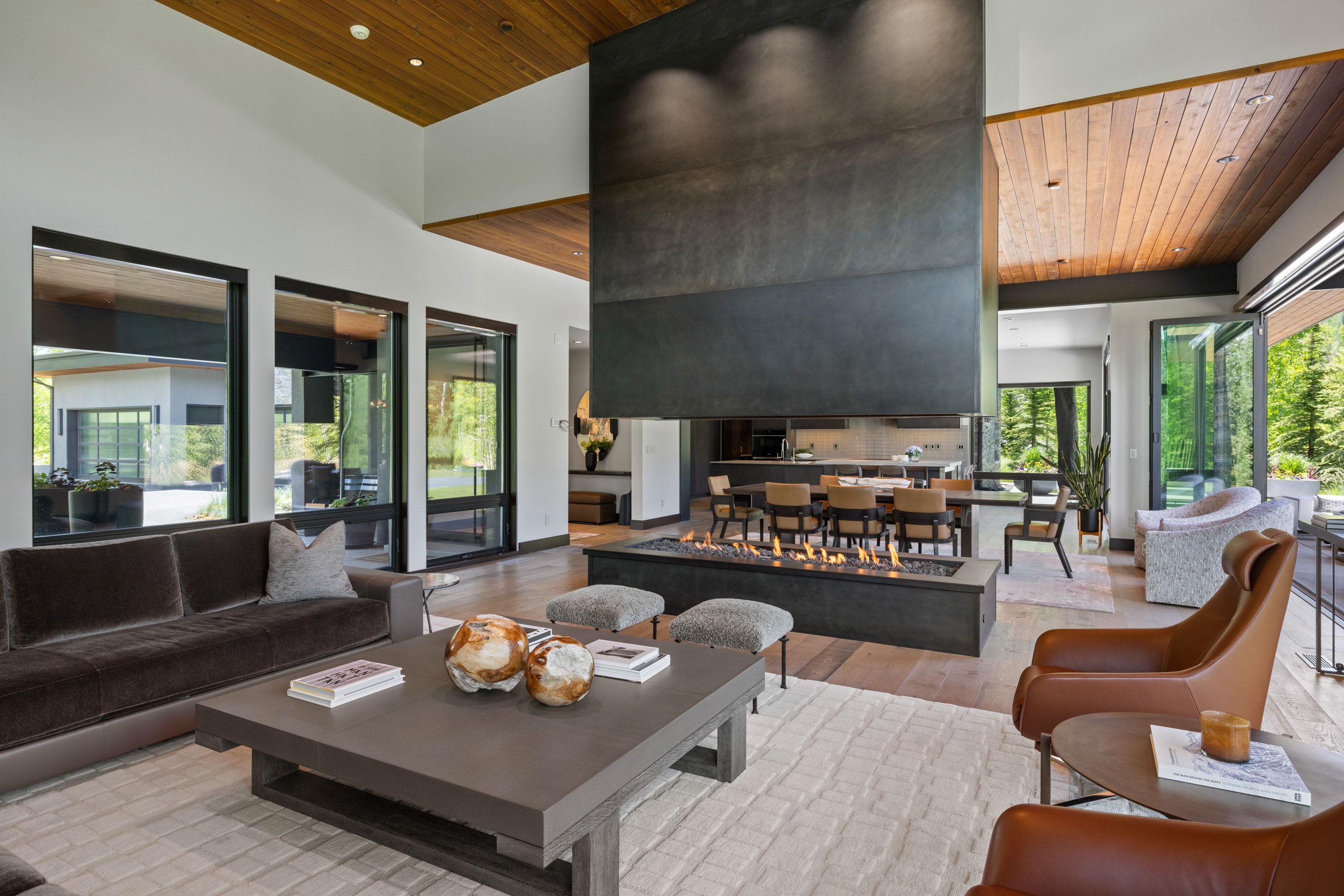 Spacious living area featuring a prominent gas fireplace with a dark-toned hood, wood-finish flooring, and a warm wood-paneled ceiling