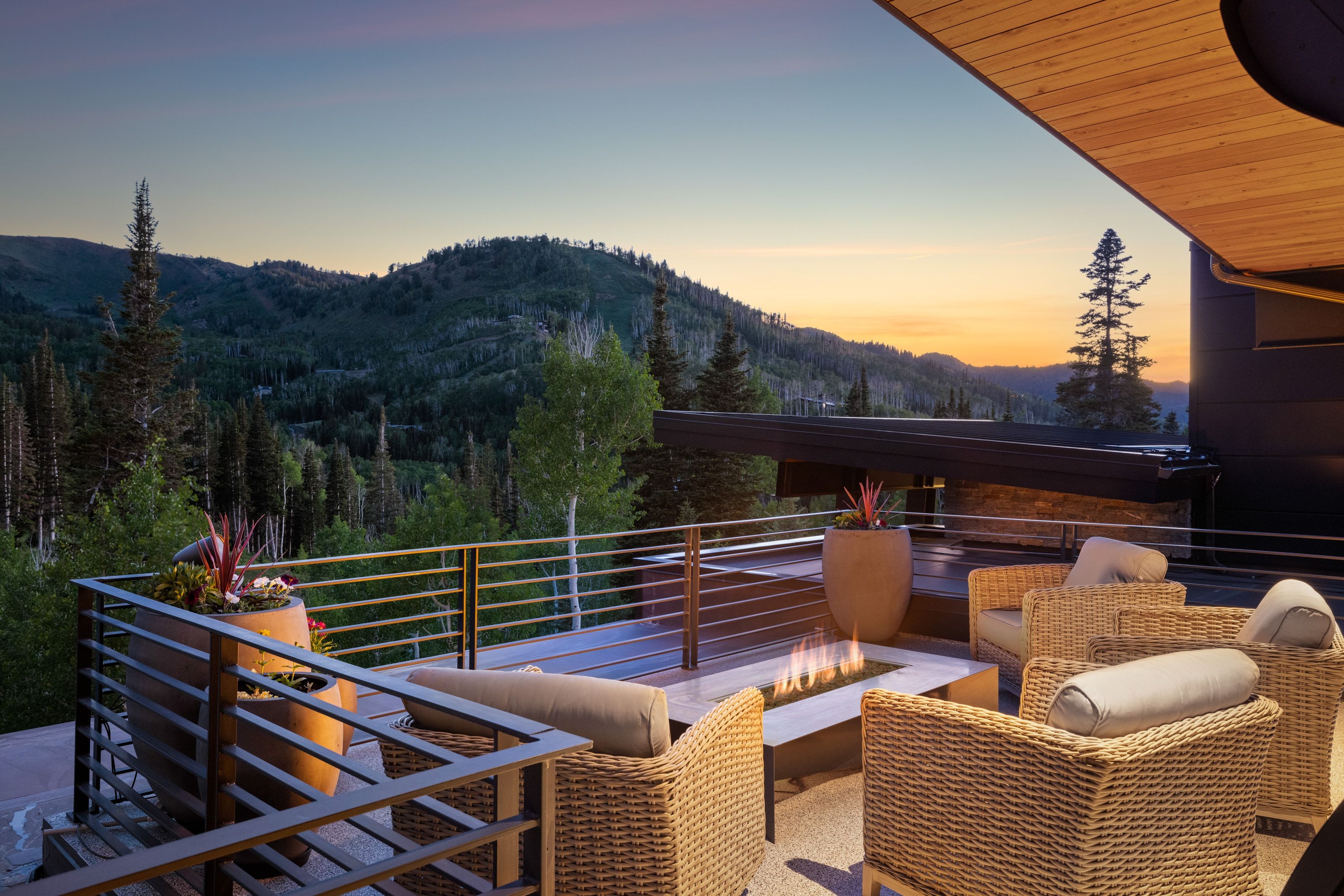 Expansive outdoor terrace featuring a built-in fire pit, metal railing, and wood ceiling paneling