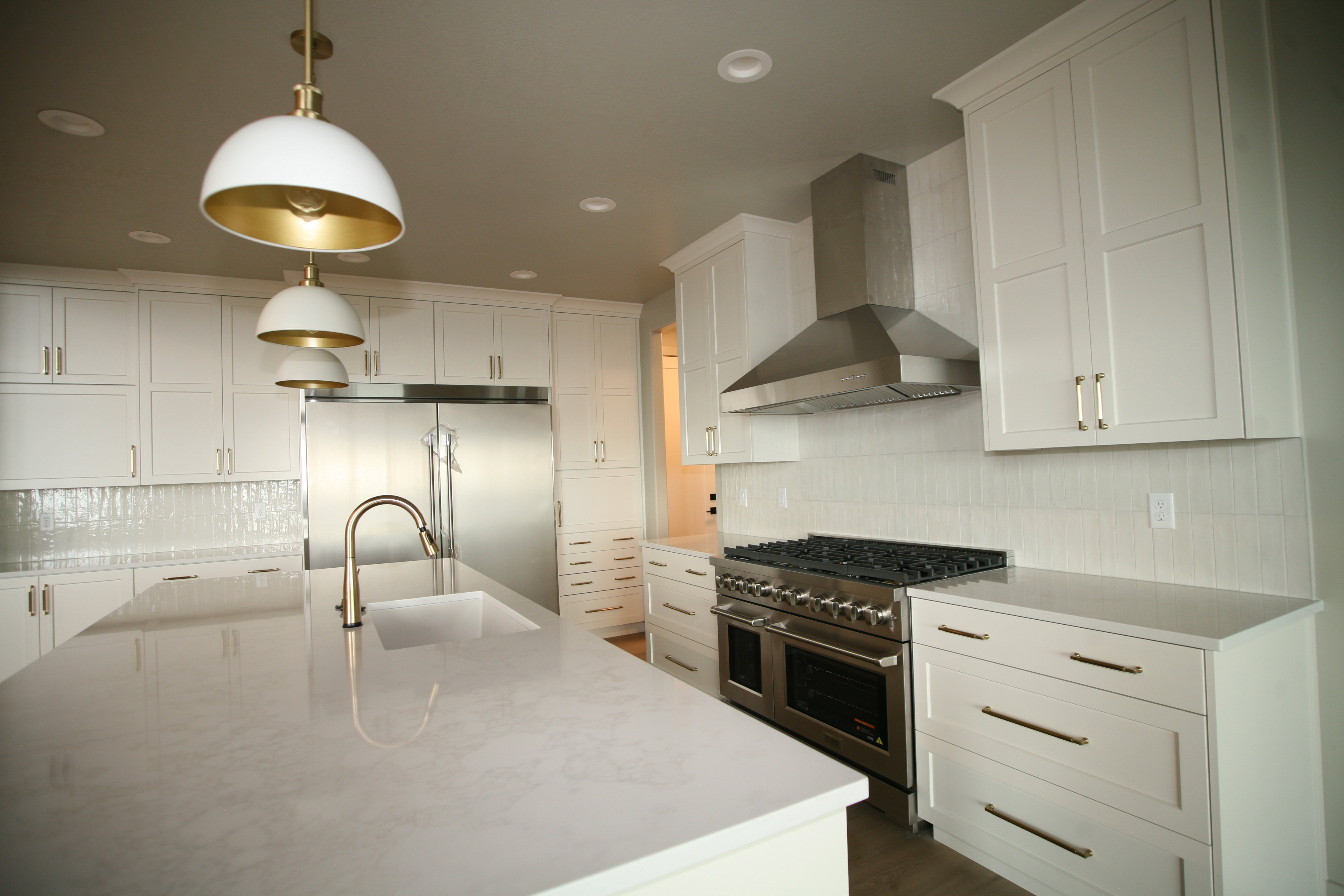 Expansive kitchen featuring white cabinetry, light-toned countertops, and two-tone pendant lighting