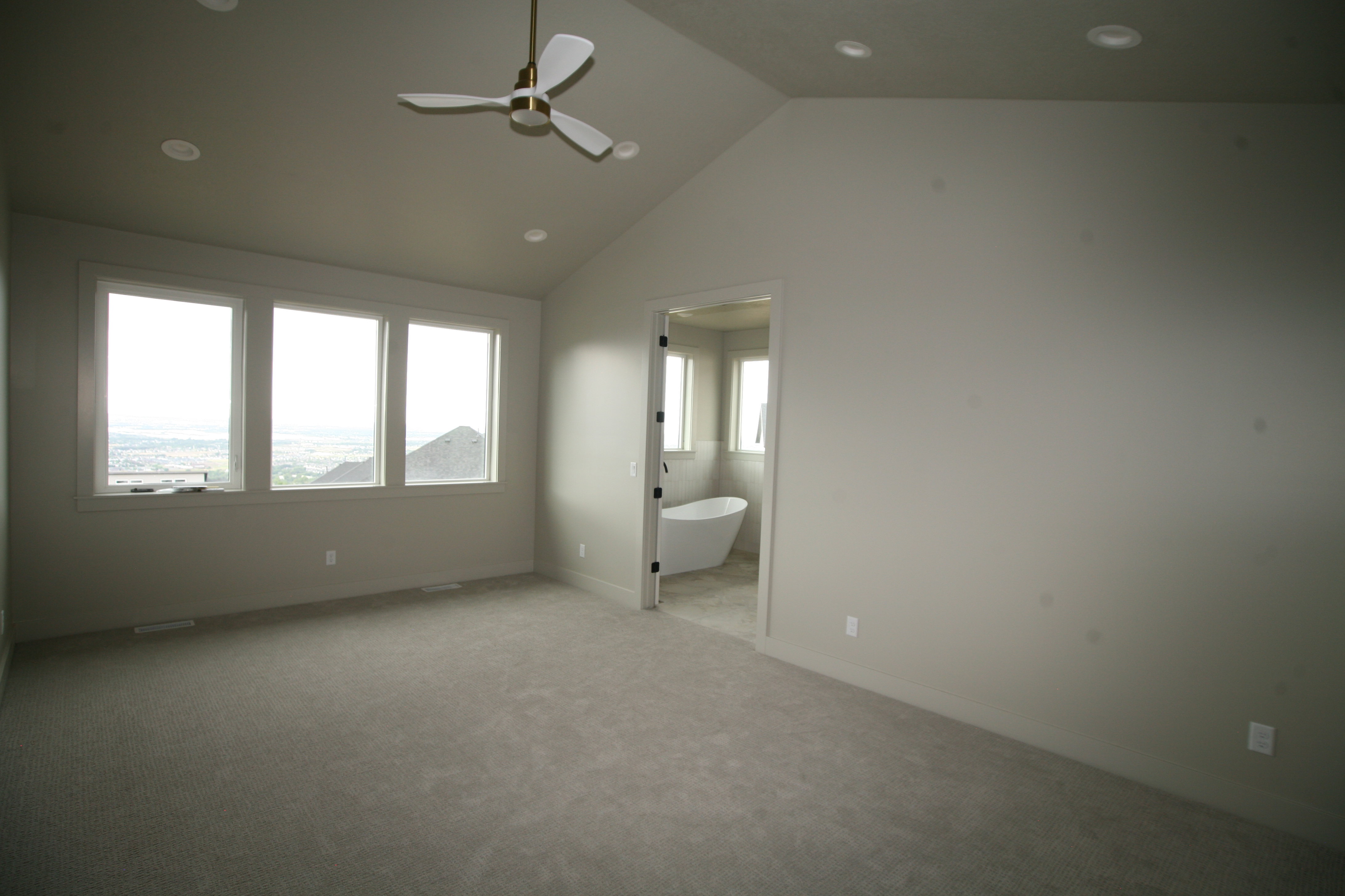 Spacious room featuring vaulted ceilings, recessed lighting, and an overhead ceiling fan