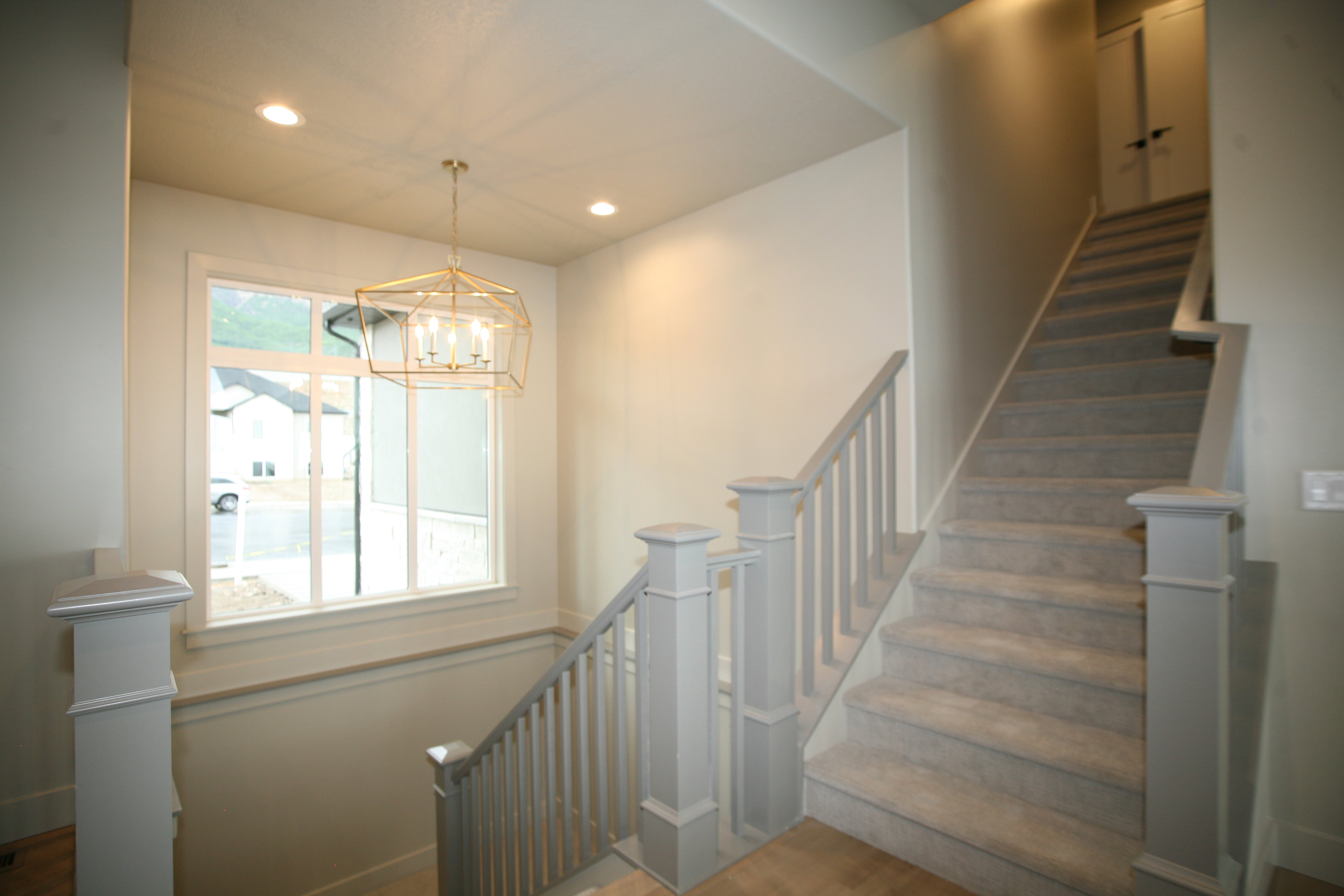Staircase featuring carpeted treads, painted balusters, and square newel posts