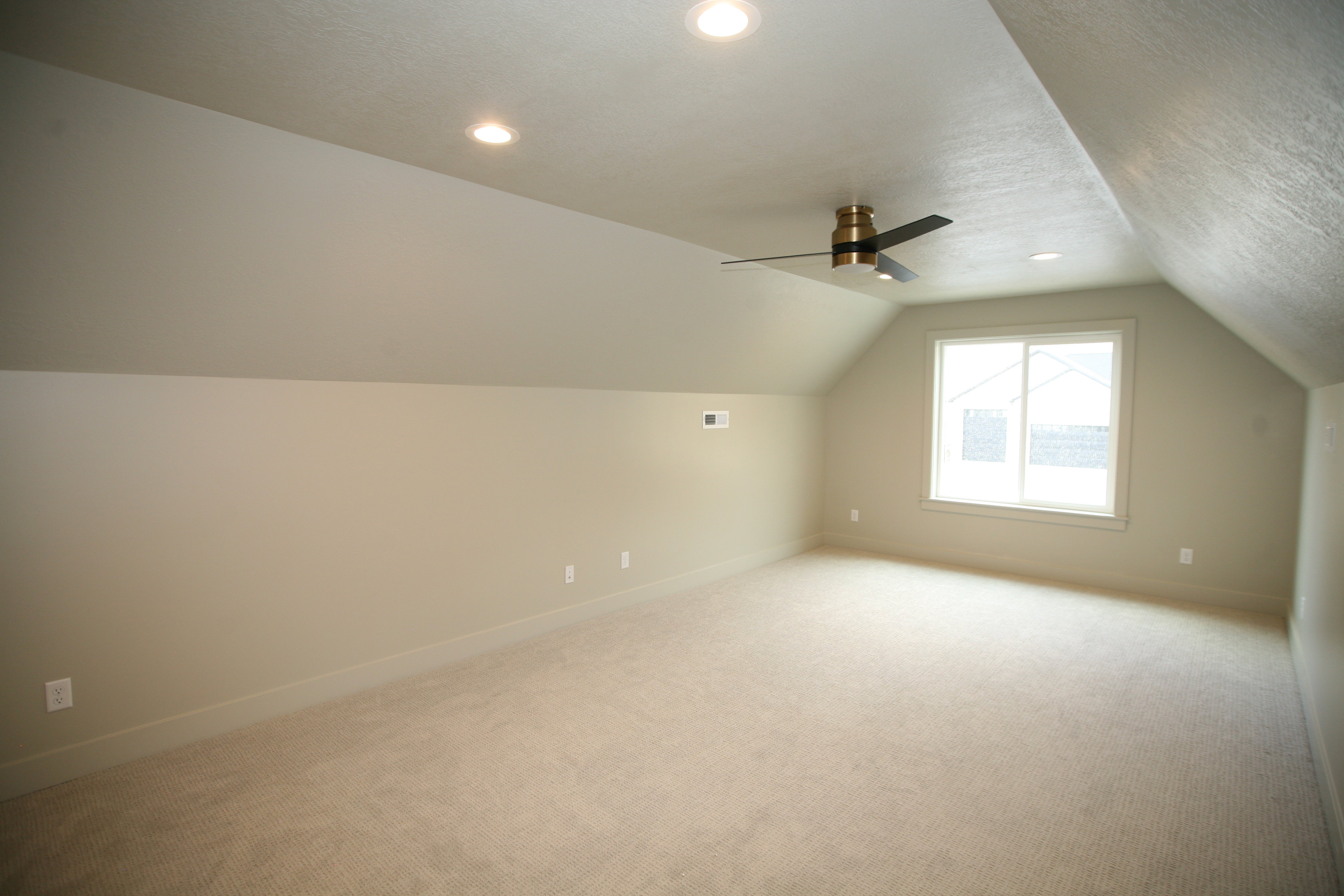 Spacious room featuring sloped ceilings, recessed lighting, a modern ceiling fan, a large window, and wall-to-wall carpeting