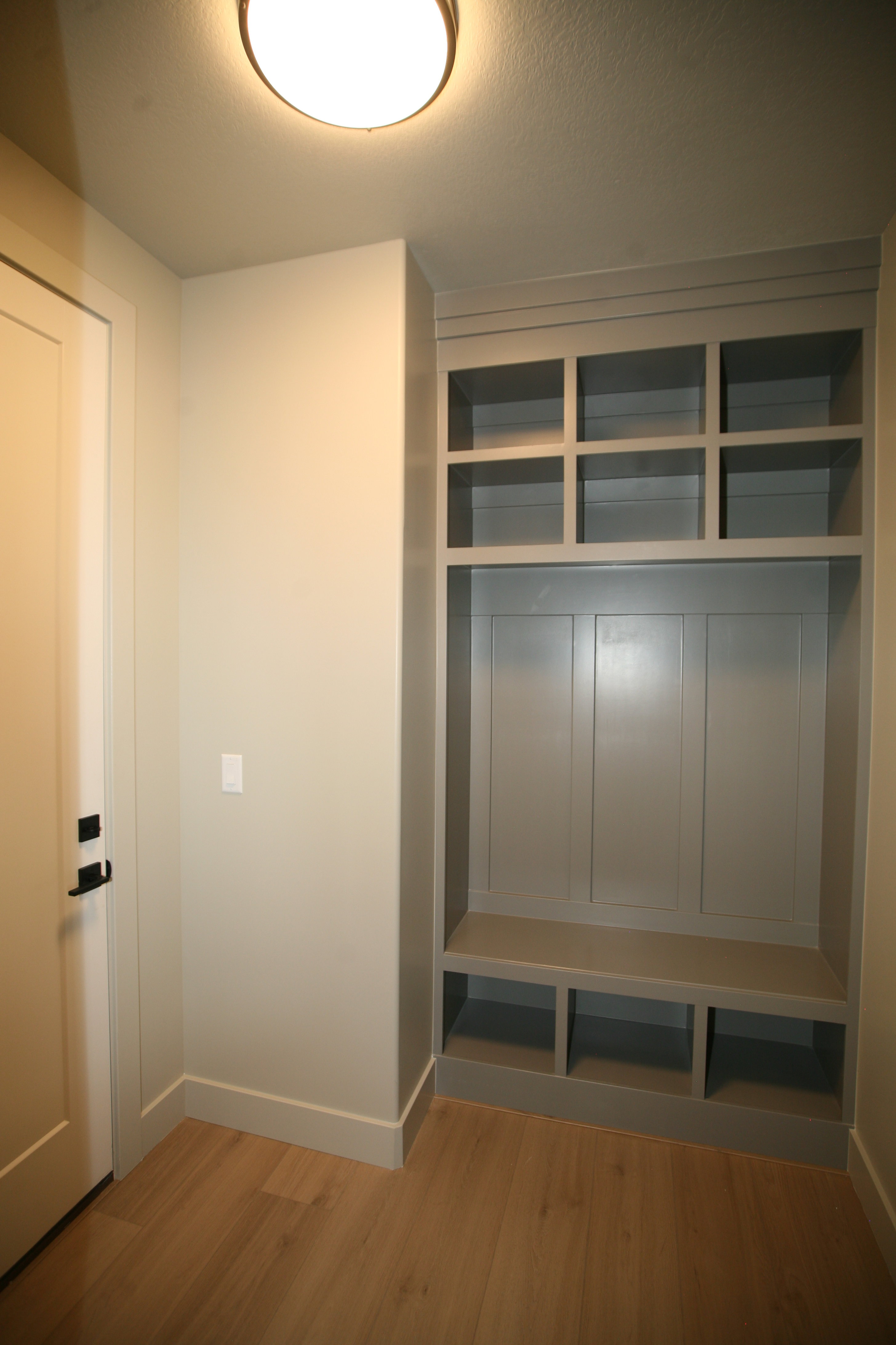 Built-in organizational unit featuring upper cubbies, board and batten paneling, a bench, and lower storage compartments