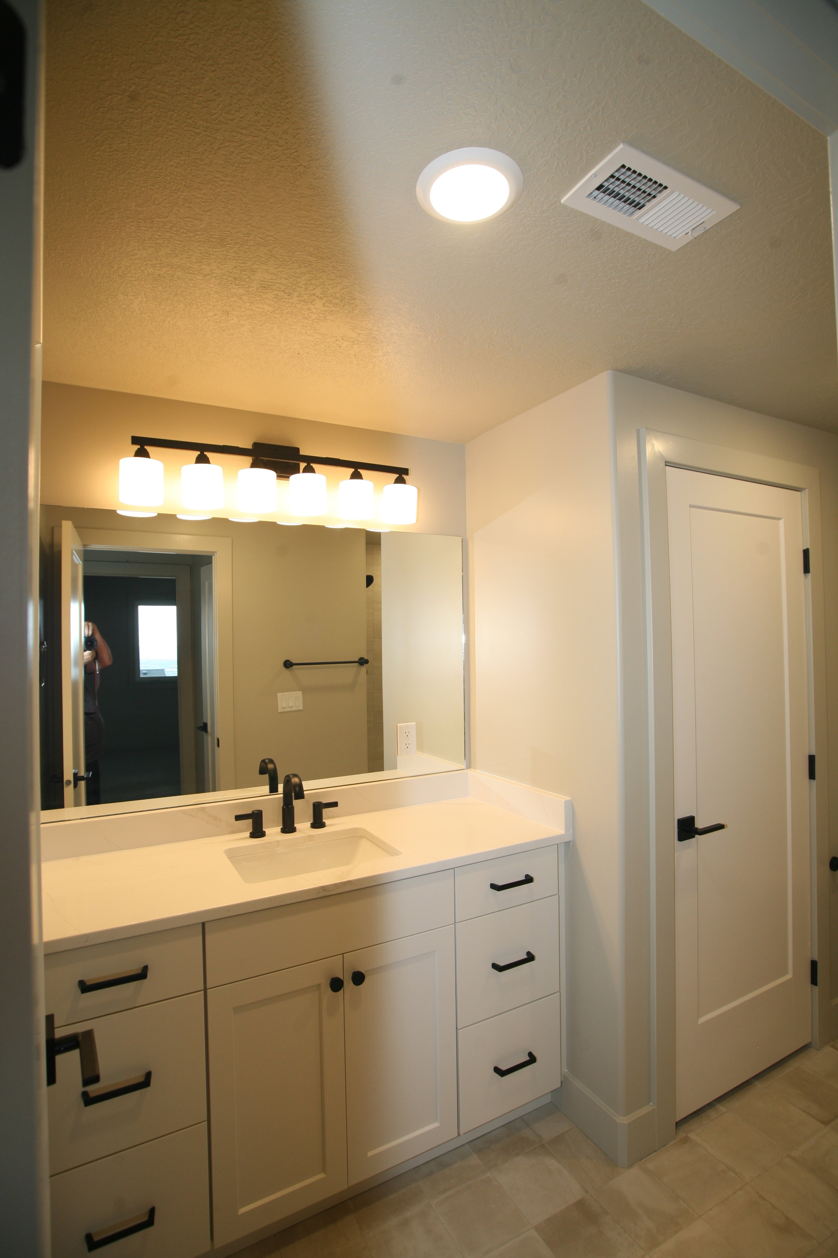 Modern bathroom vanity featuring white cabinetry with matte black hardware, a rectangular undermount sink, and a white countertop