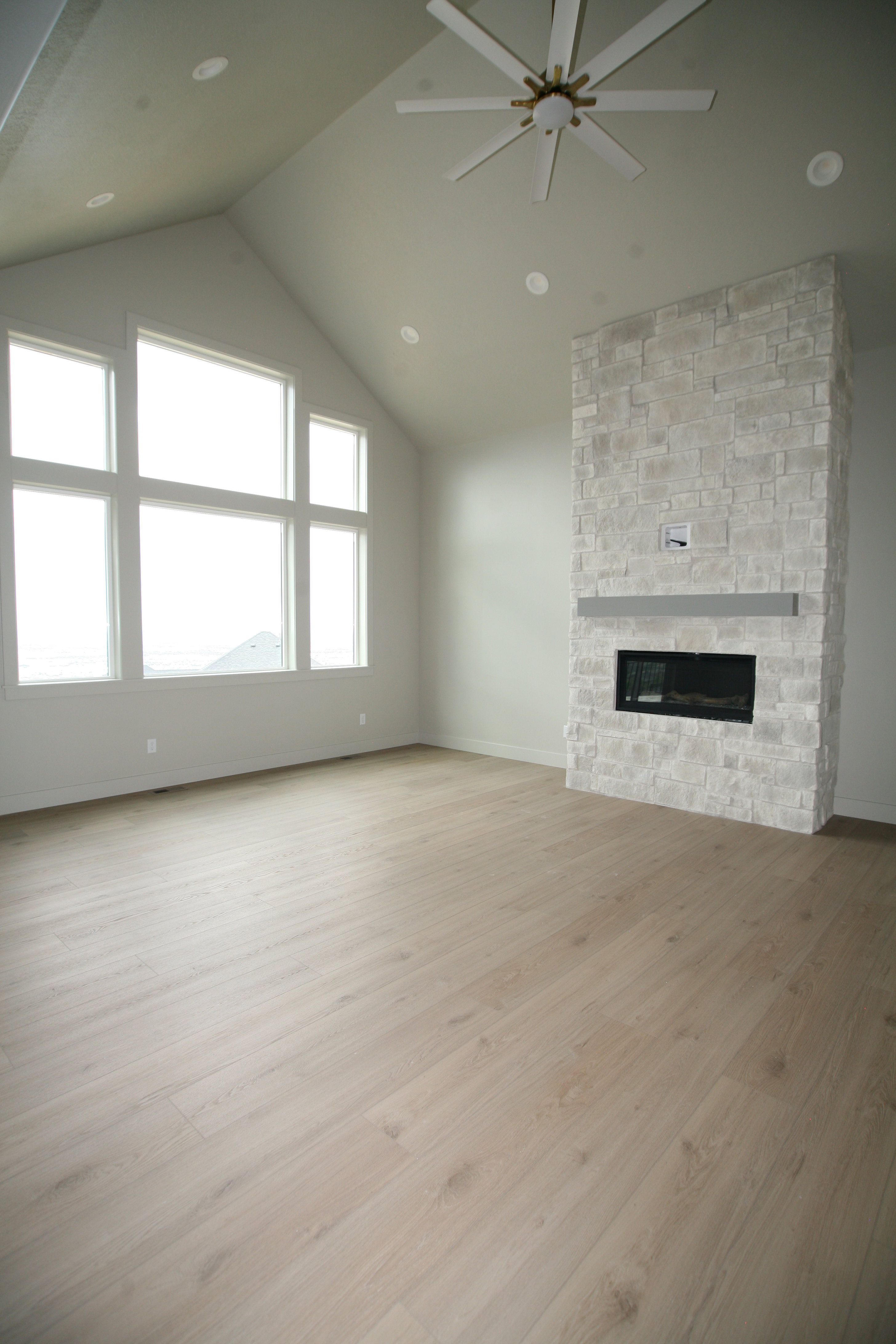 Spacious room featuring vaulted ceilings, a contemporary ceiling fan, and recessed lighting