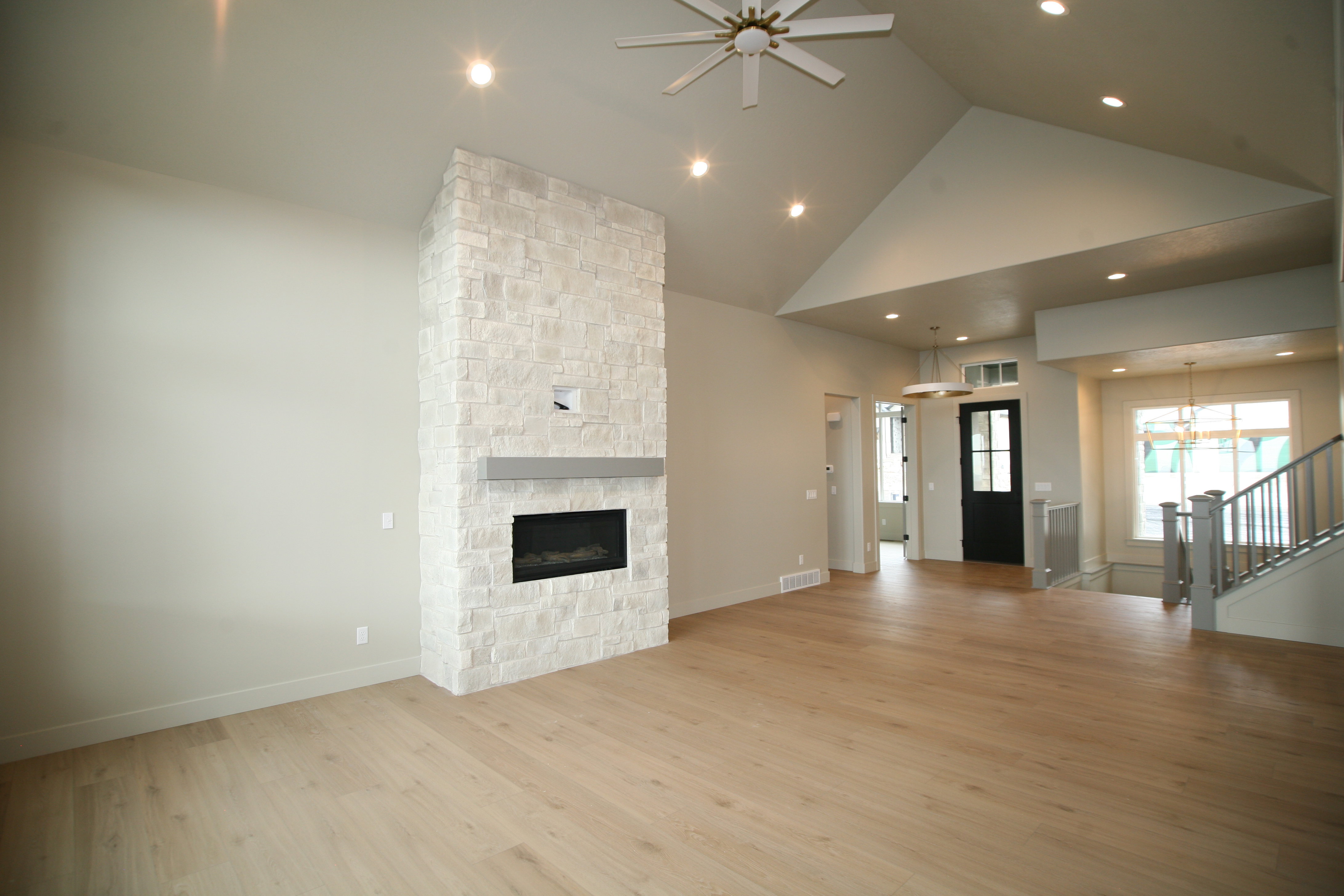 Spacious room featuring vaulted ceilings, recessed lighting, and light wood-finish flooring