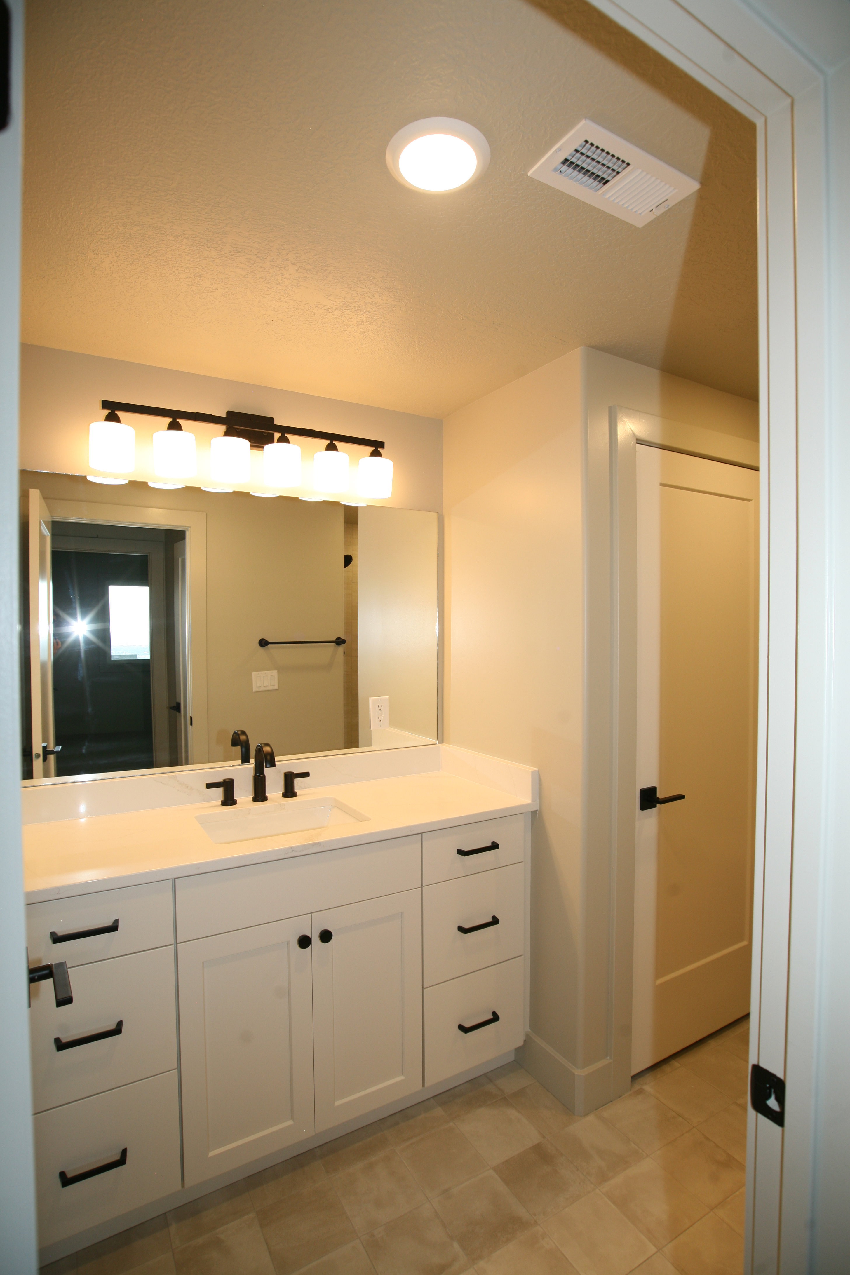 Bathroom vanity featuring a single rectangular undermount sink, a white countertop, and matte black fixtures