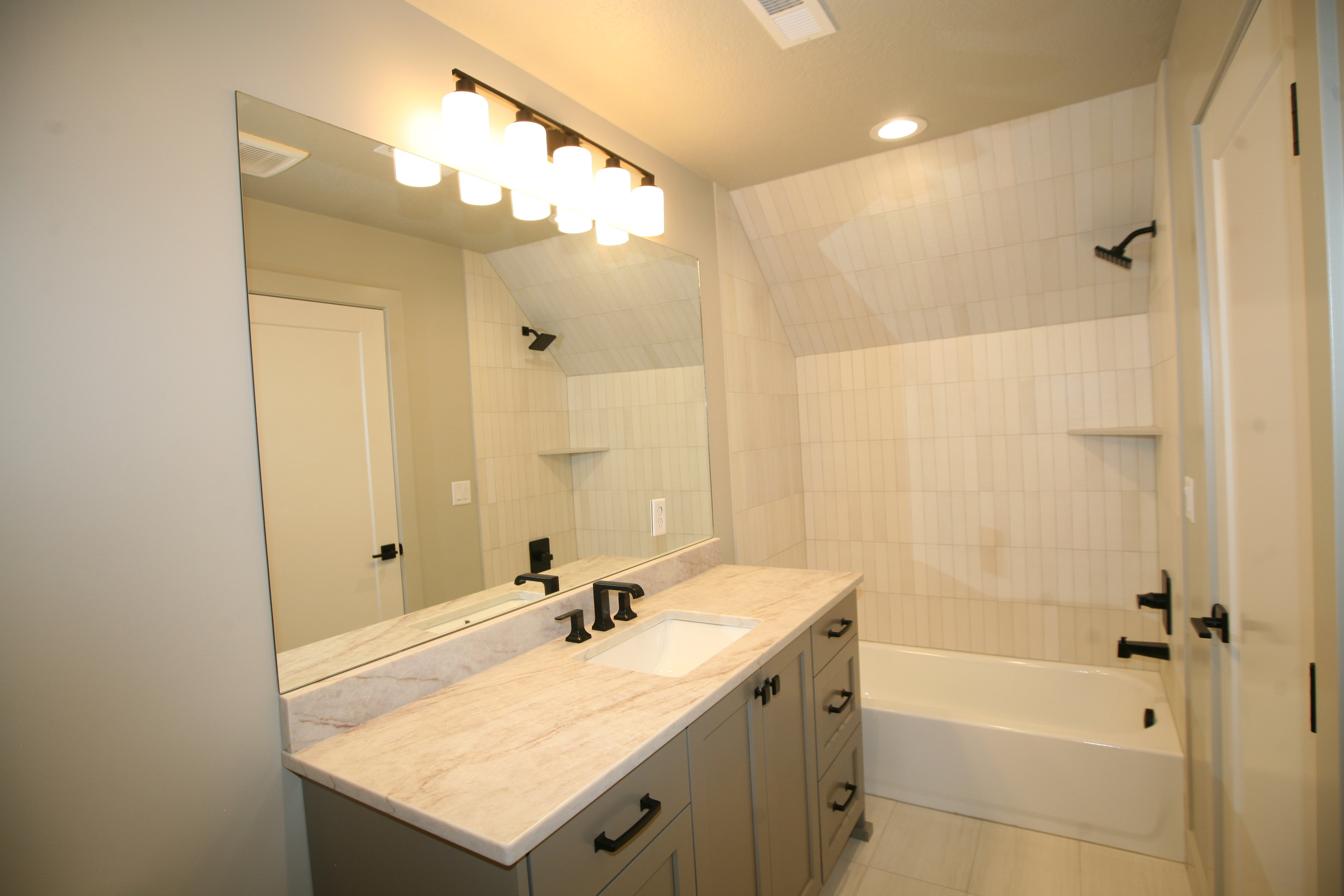 Bathroom featuring a large vanity with an integrated sink, stone-look countertop, and dark-finished hardware
