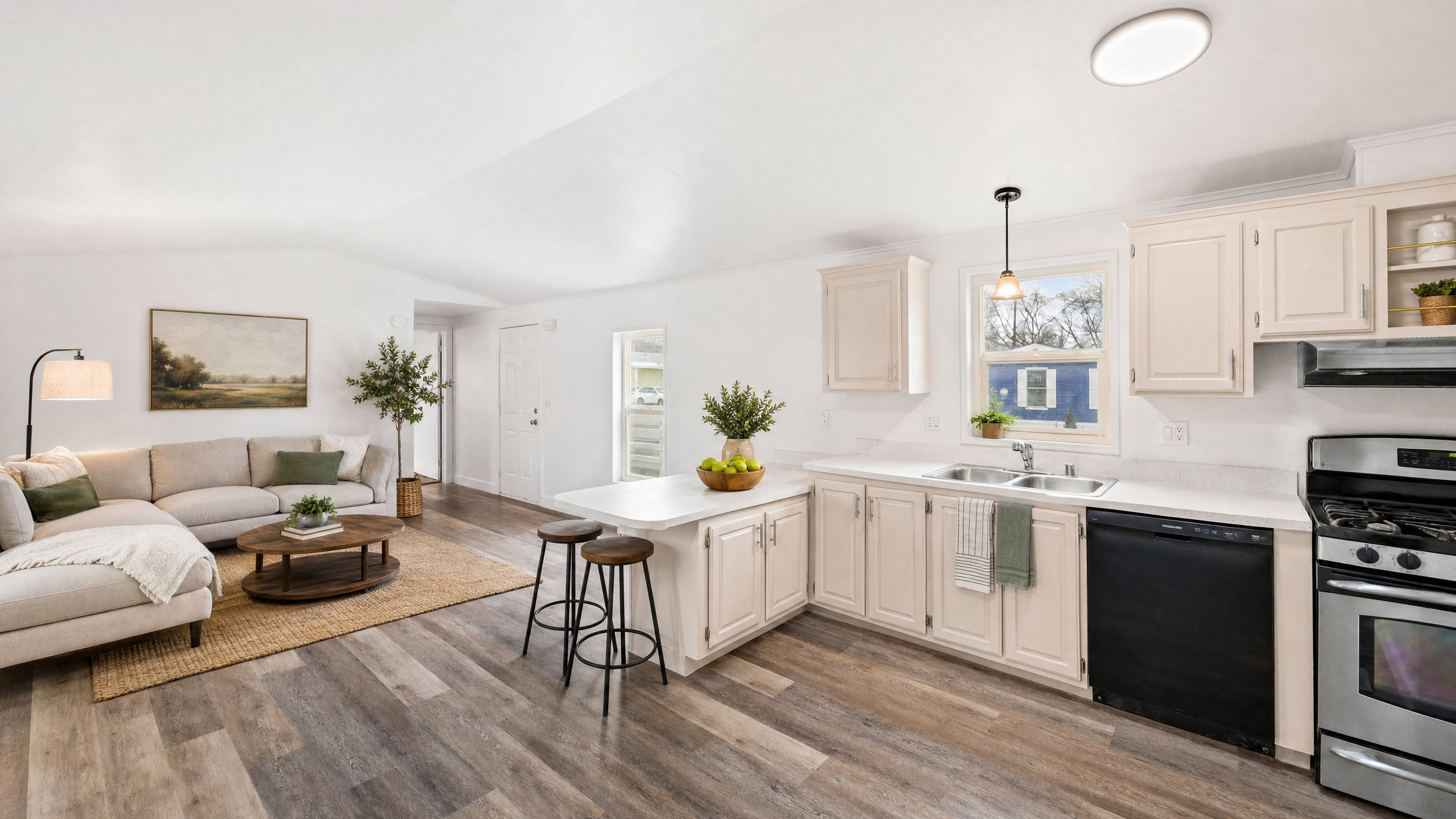 Open-concept living space featuring wood-finish flooring, white walls, and vaulted ceilings