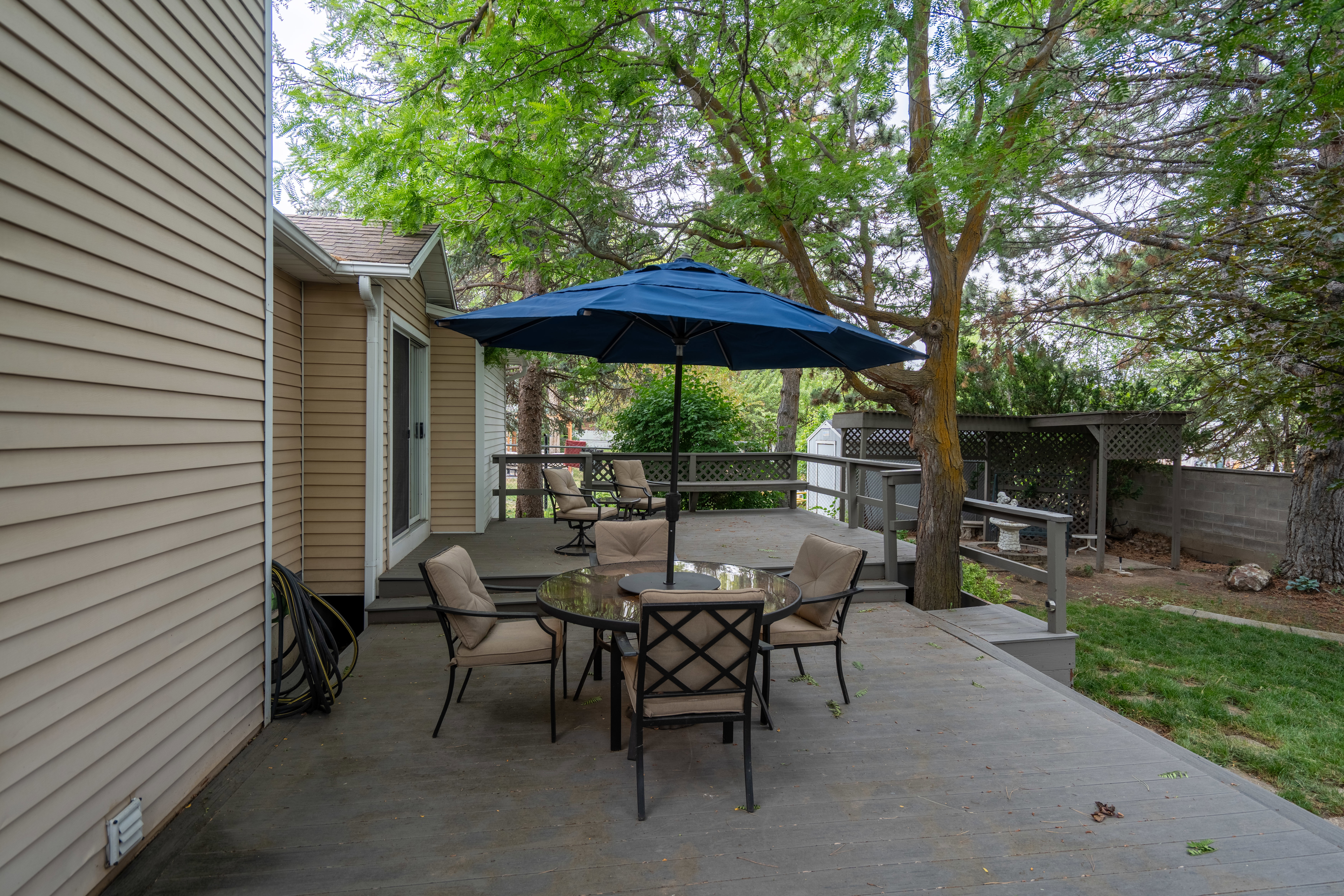 Spacious exterior deck with neutral siding and mature trees