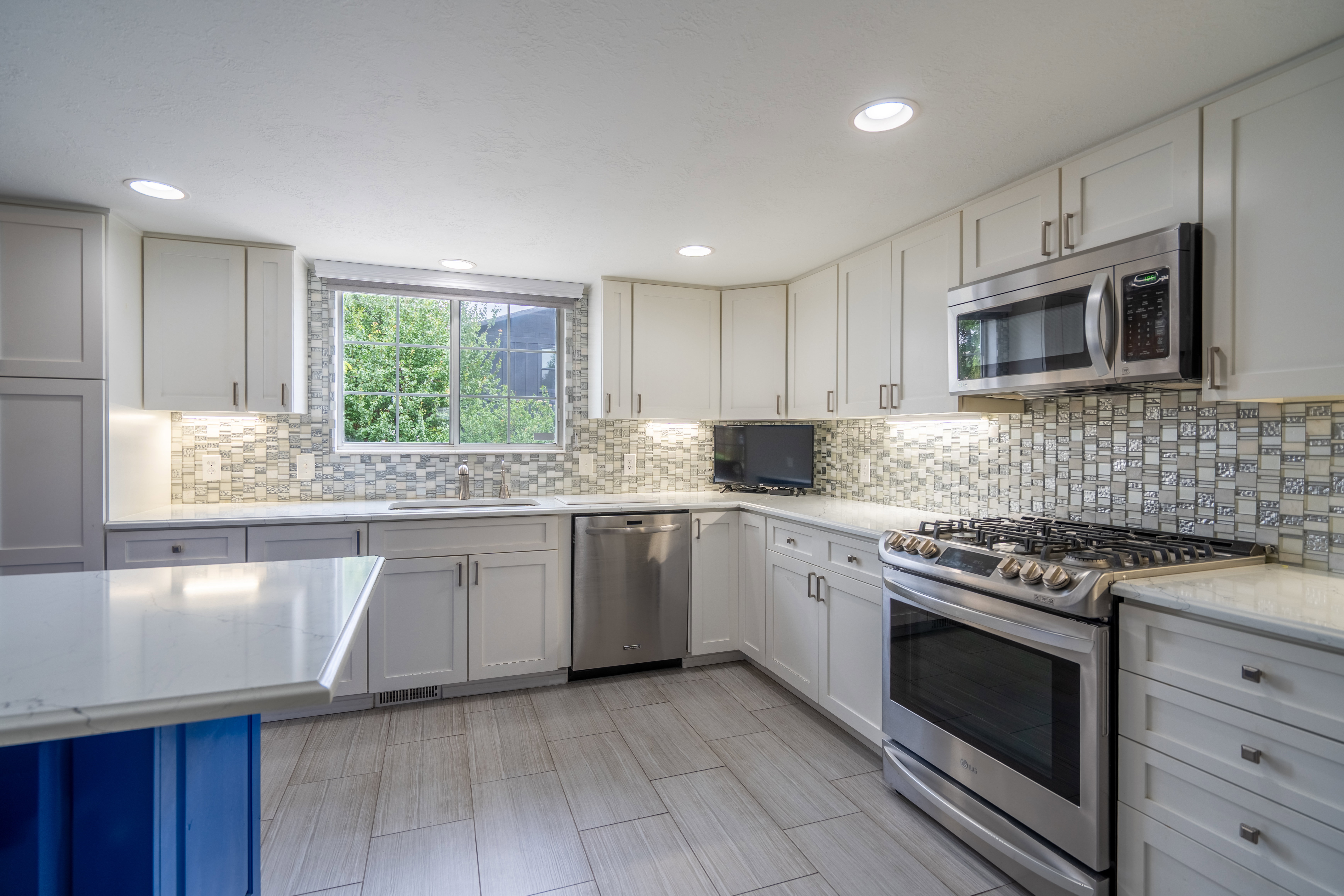 Contemporary kitchen featuring white cabinetry, light countertops, and a full tile backsplash