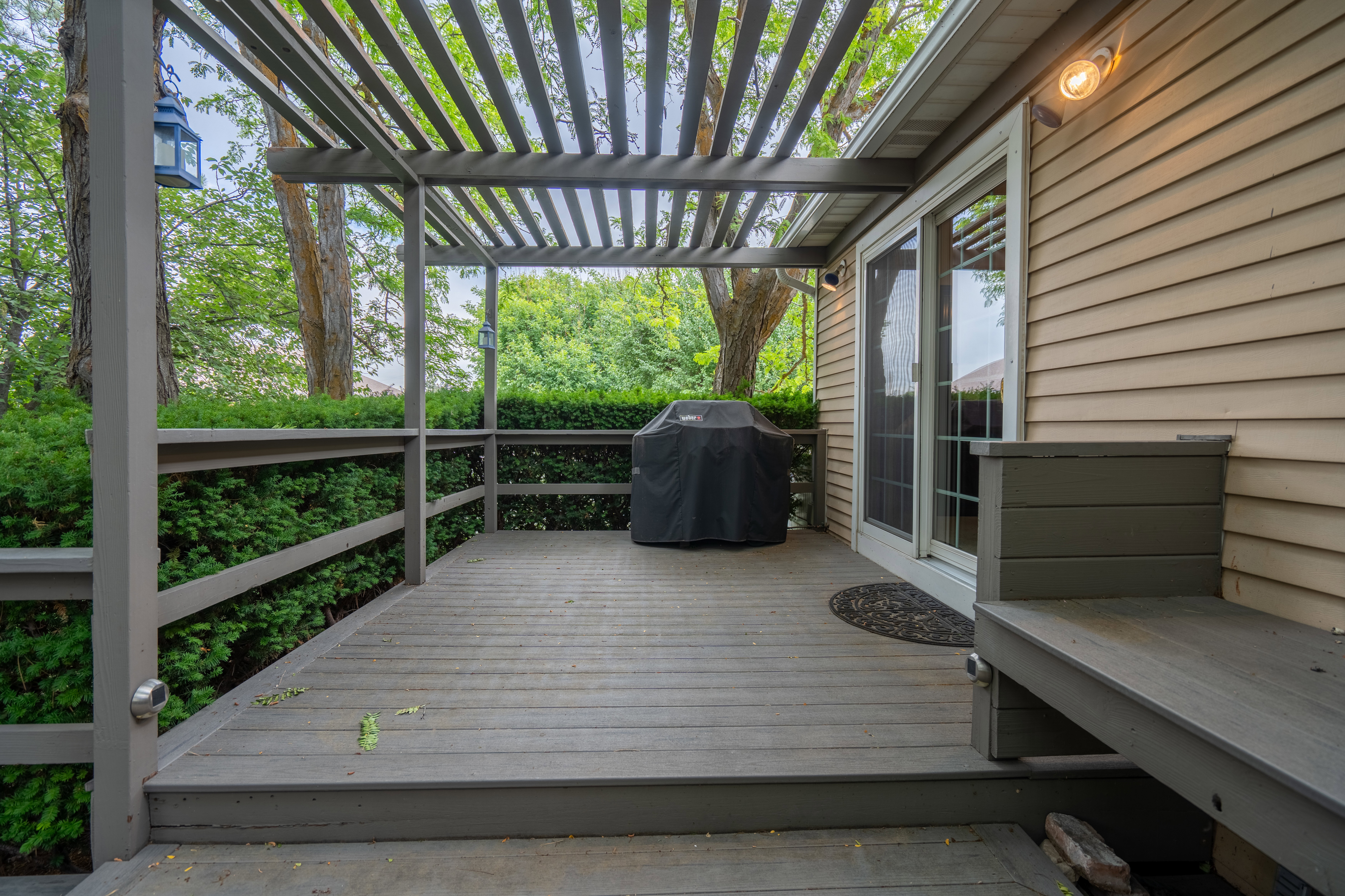 Expansive outdoor deck featuring a slat pergola, built-in bench seating, and direct access through sliding glass doors