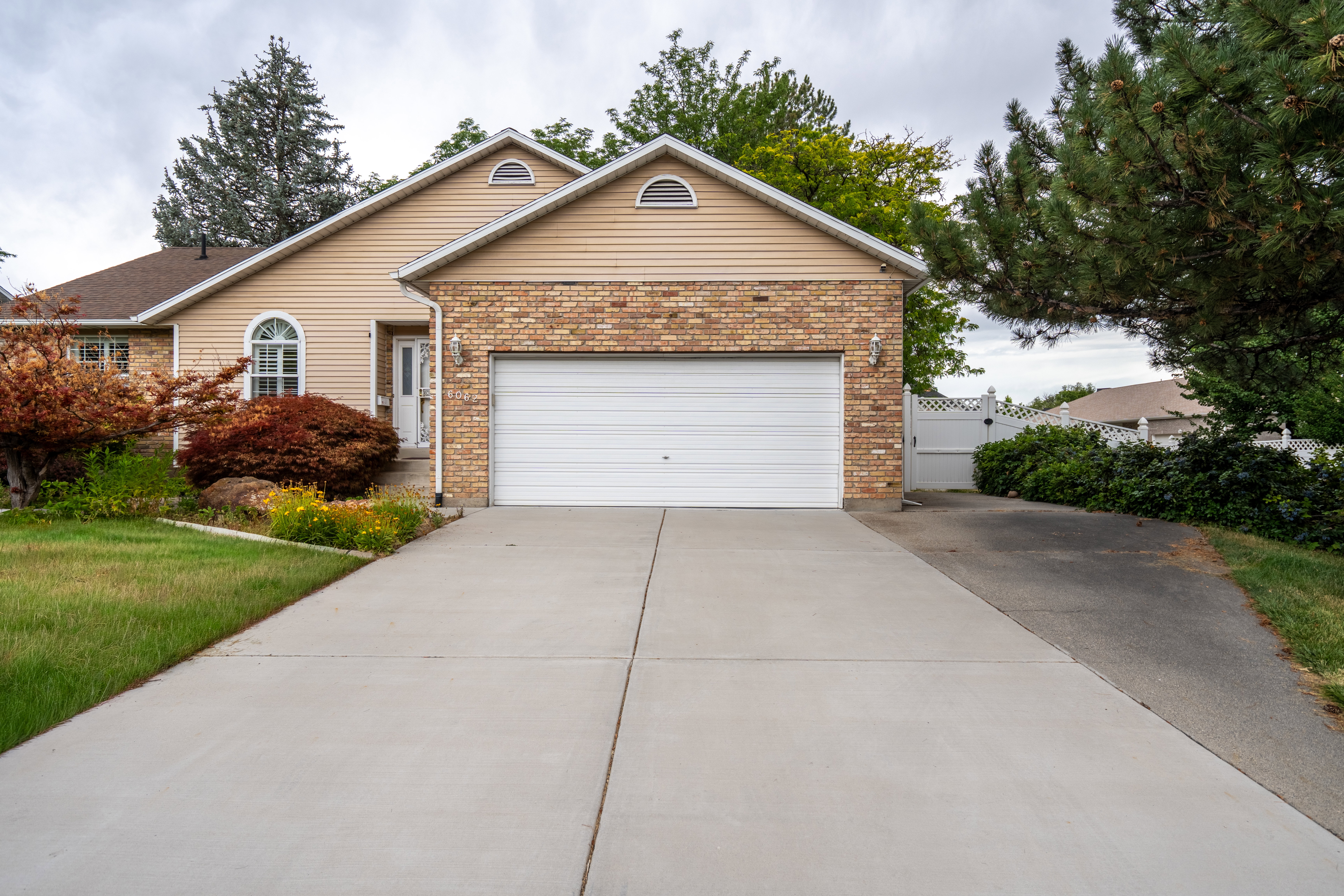 Exterior featuring a brick facade, beige siding, white garage door