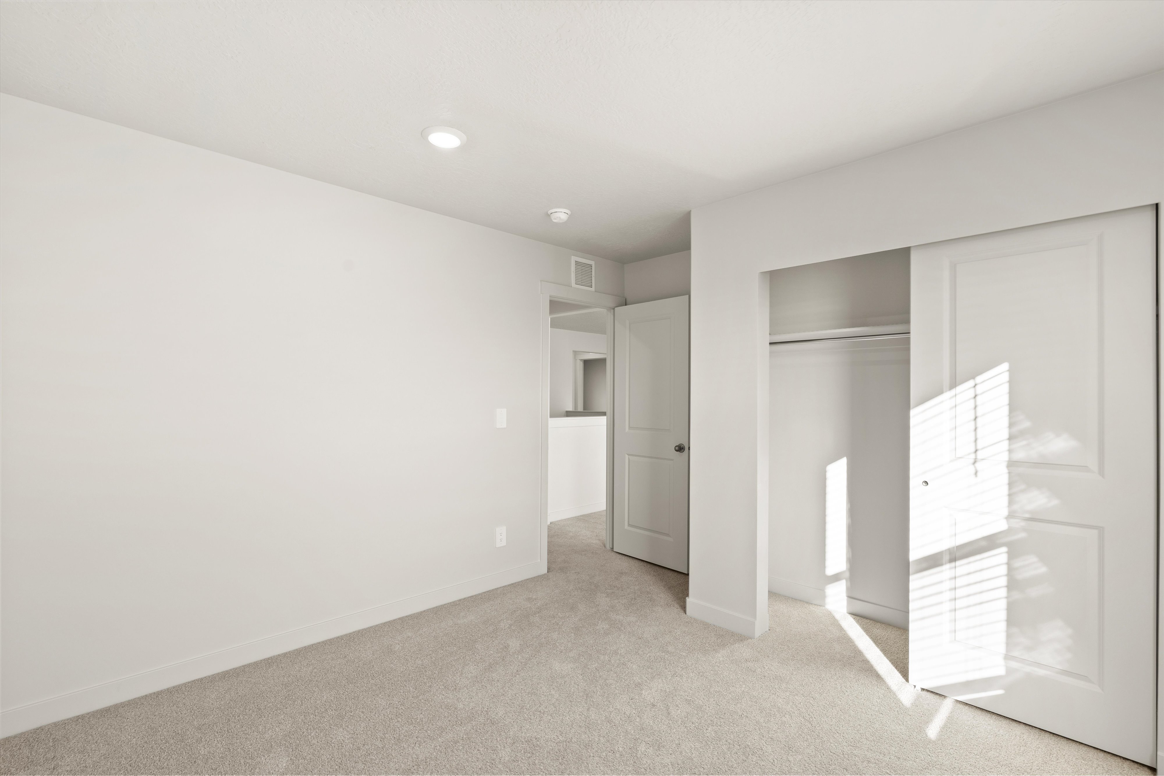 Carpeted room featuring a double-door closet with a hanging rod and shelf