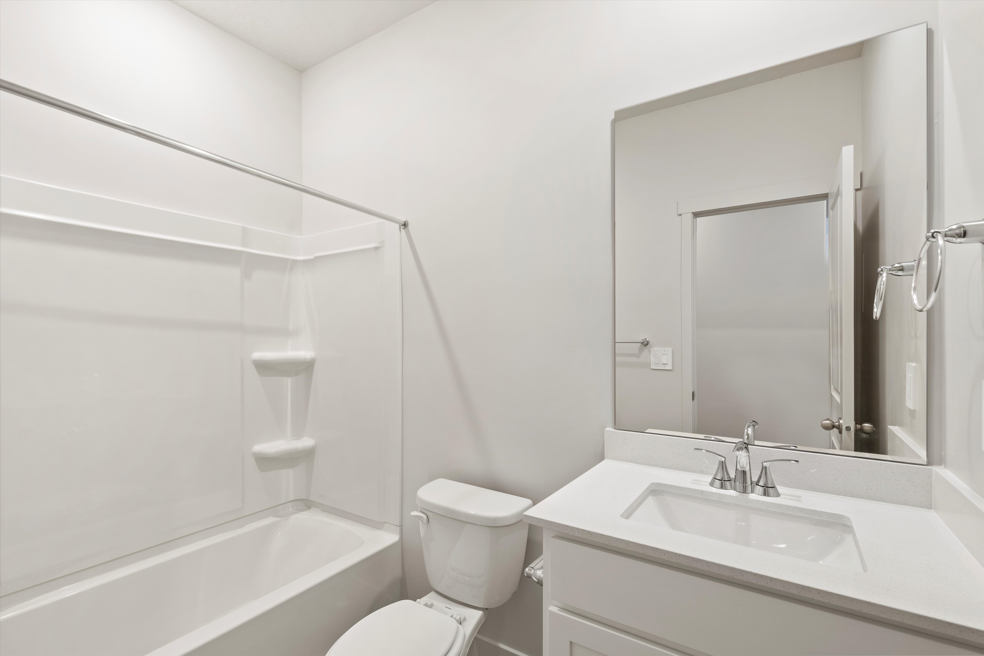 Full bathroom featuring a white tub/shower combination, white toilet, and a vanity with a white countertop and integrated sink