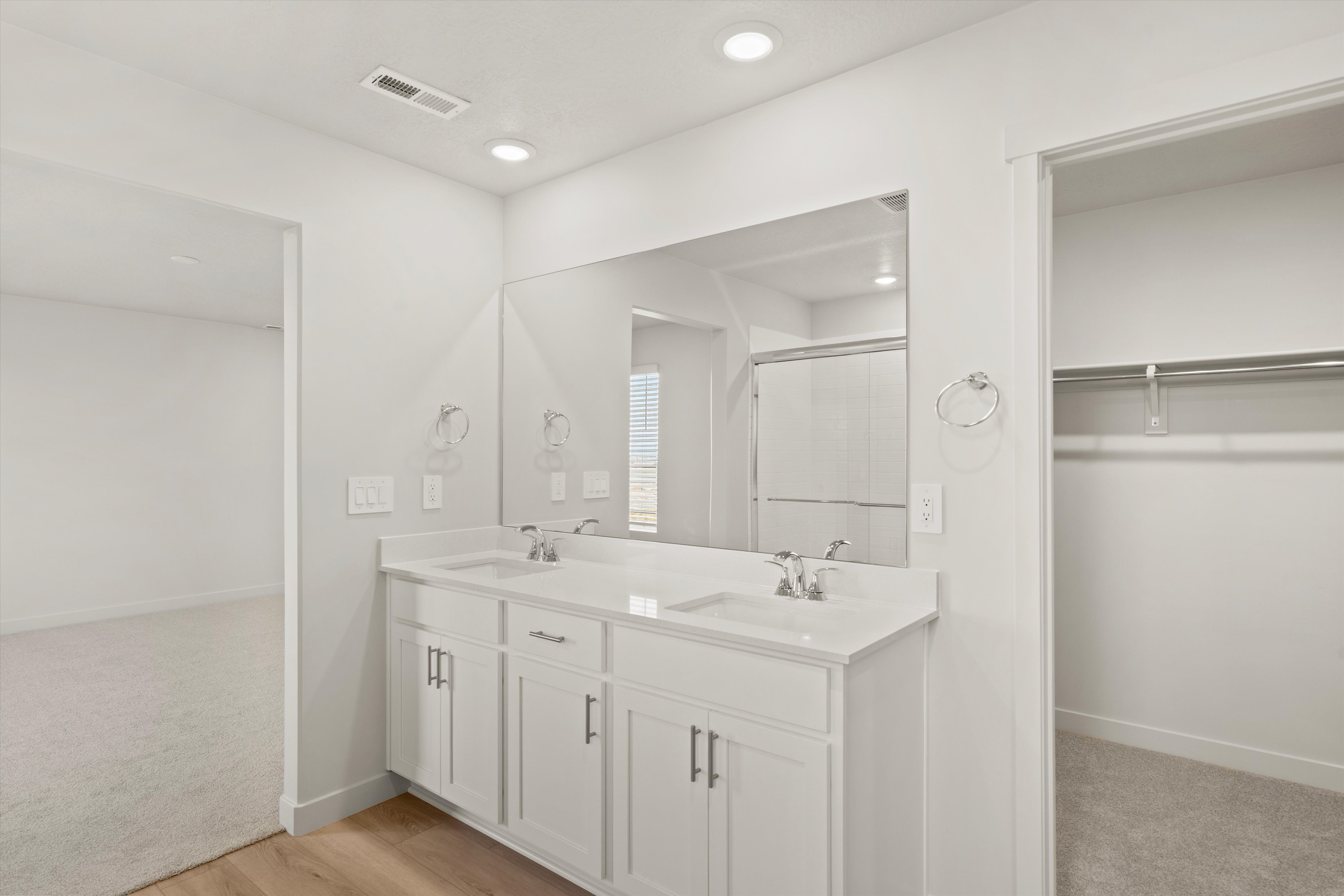Dual vanity featuring white shaker cabinetry, undermount sinks, and a large wall-mounted mirror