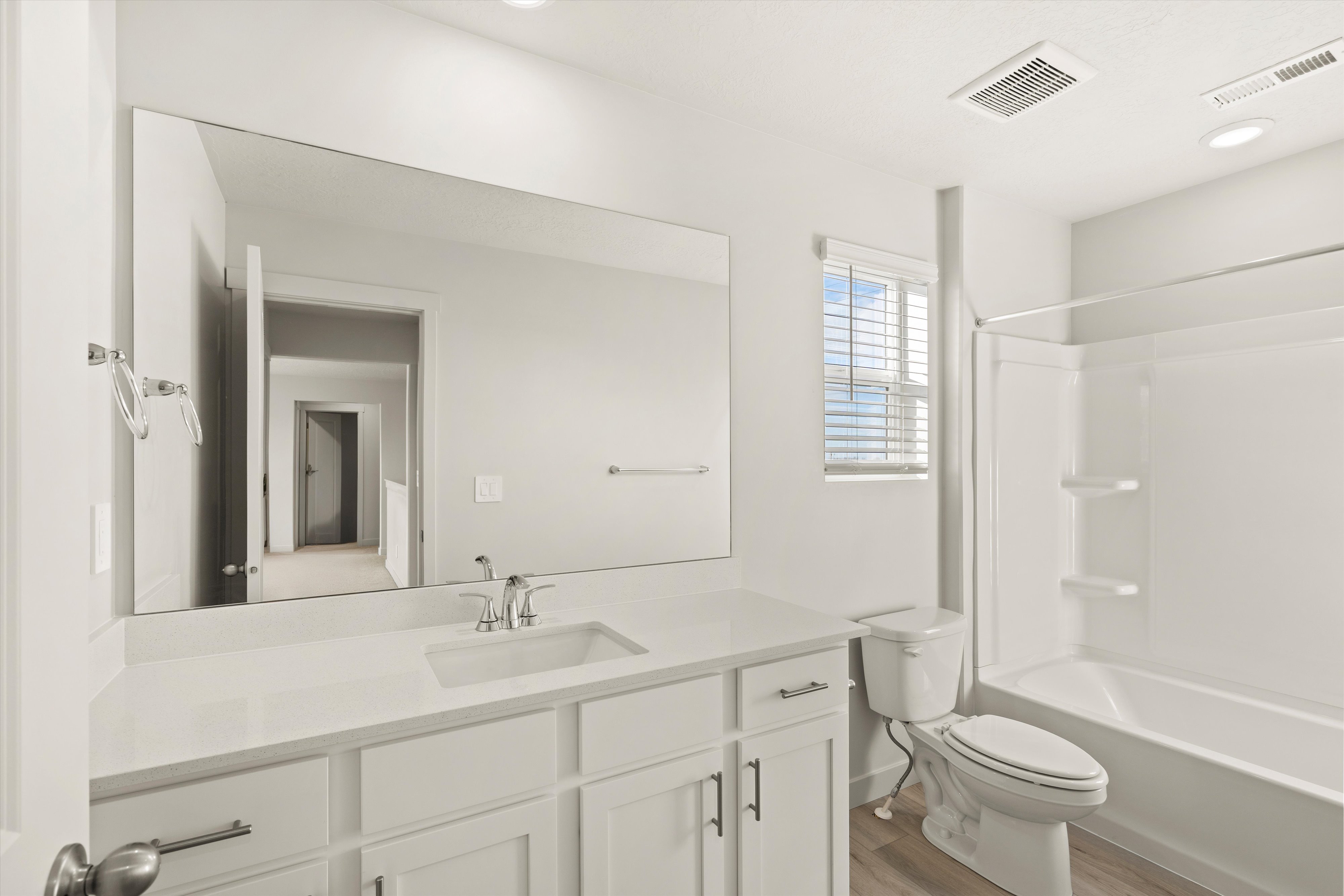 Contemporary bathroom featuring a spacious vanity with an integrated sink, polished chrome faucet, and expansive wall-mounted mirror