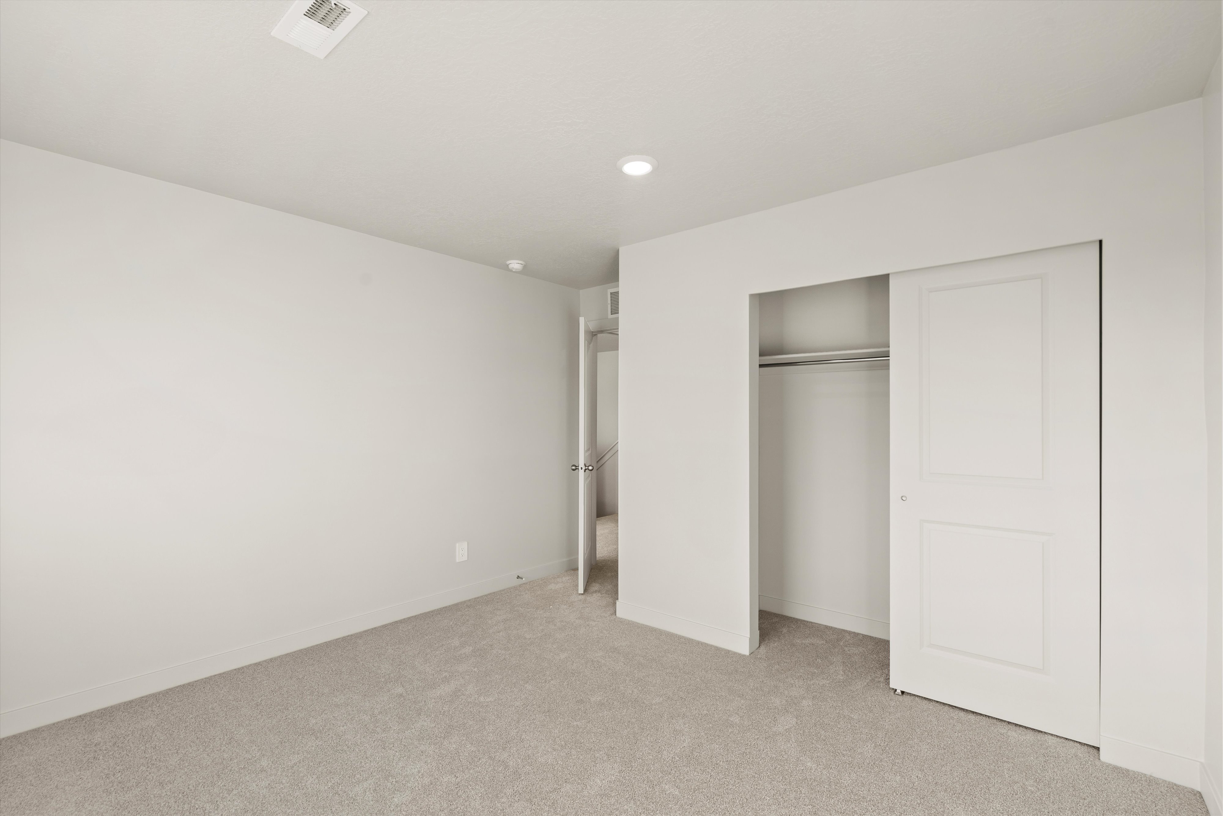 Carpeted room featuring a double-door closet with a hanging rod, recessed lighting, and a neutral wall color