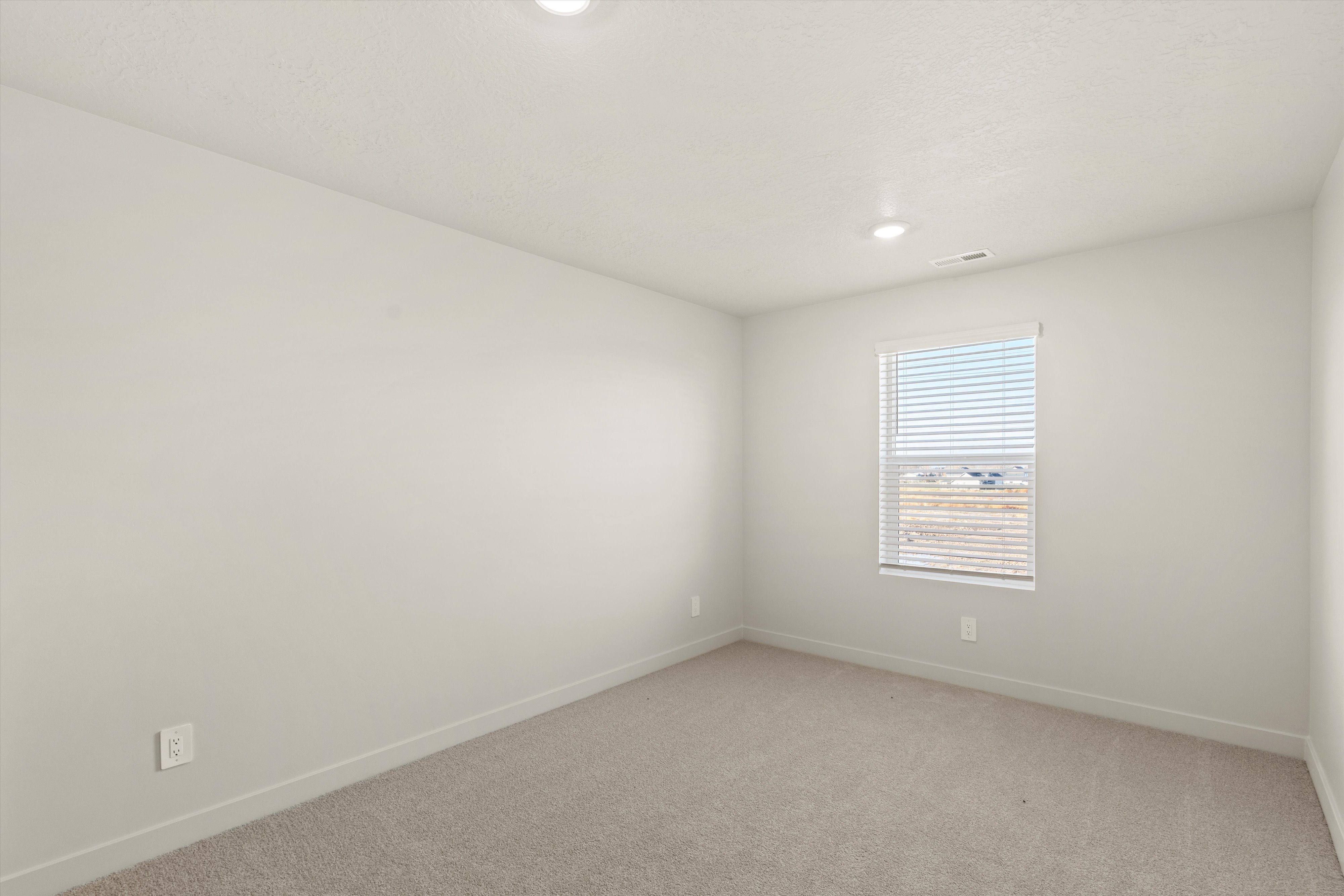 Bright interior space featuring neutral wall paint, recessed lighting, a single window with horizontal blinds, carpeting, and baseboard trim