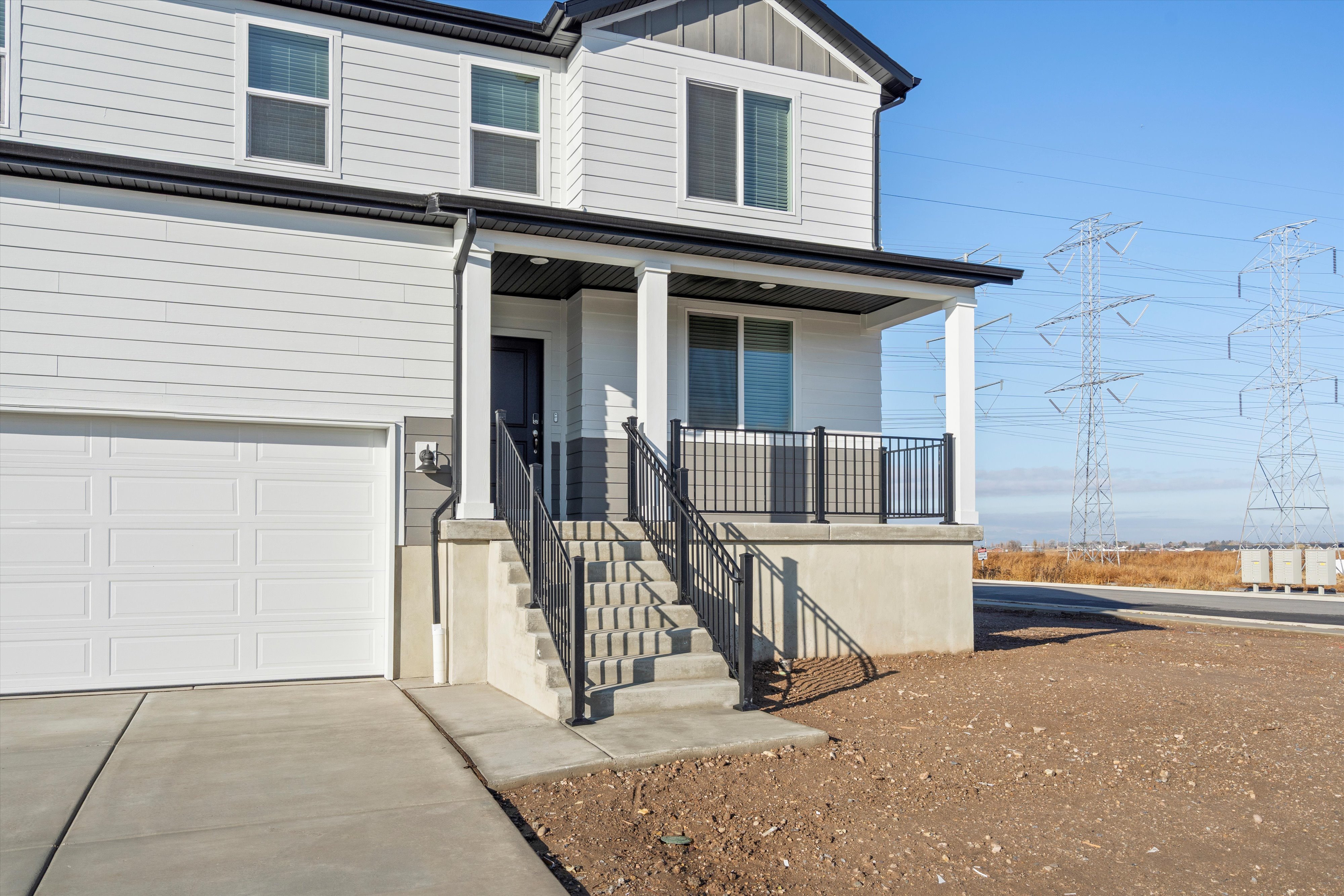 Exterior featuring horizontal siding, a covered porch with white columns and black railings, and a panel garage door