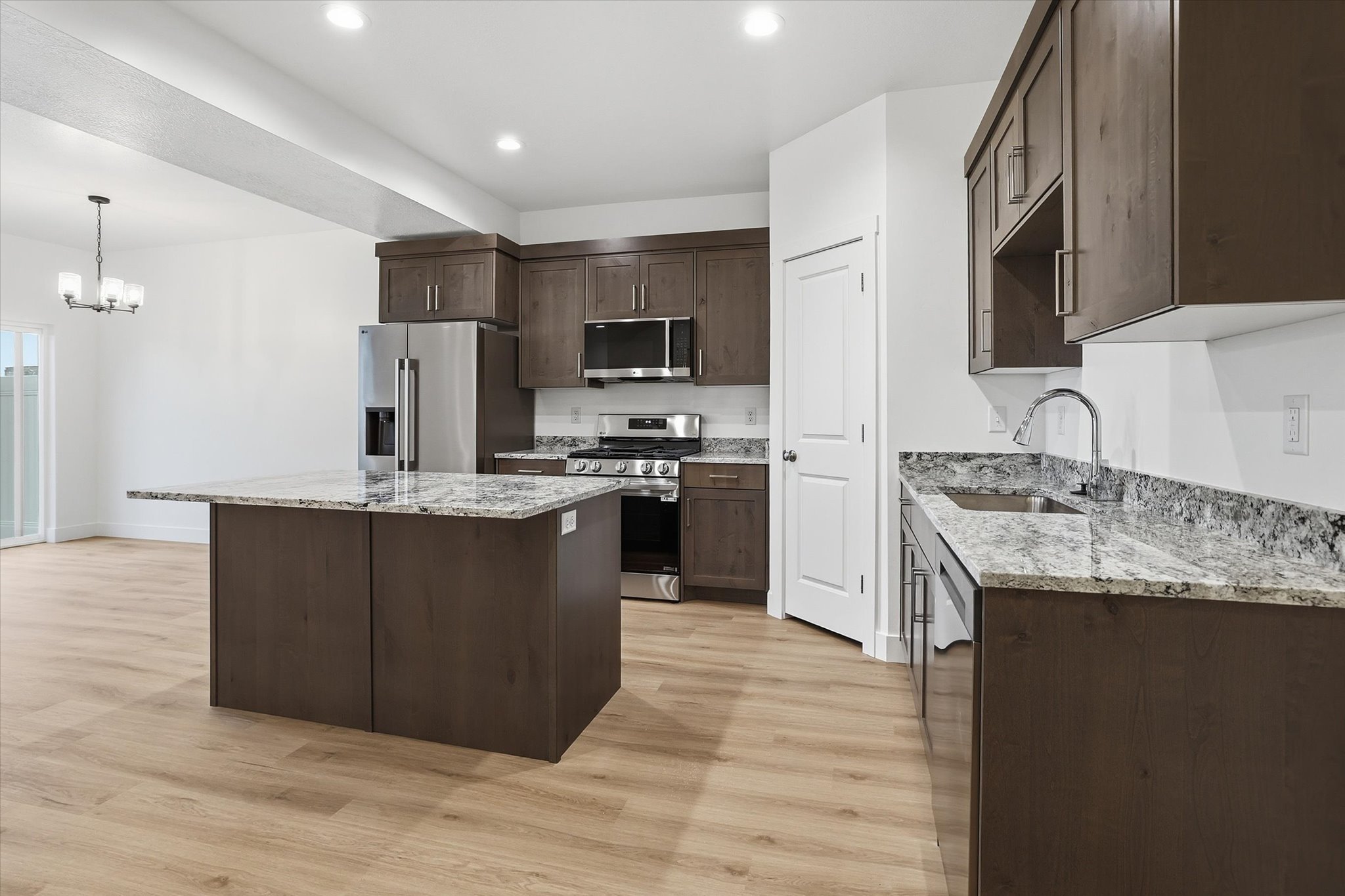 Contemporary kitchen featuring wood-finish cabinetry, granite countertops, and stainless steel appliances