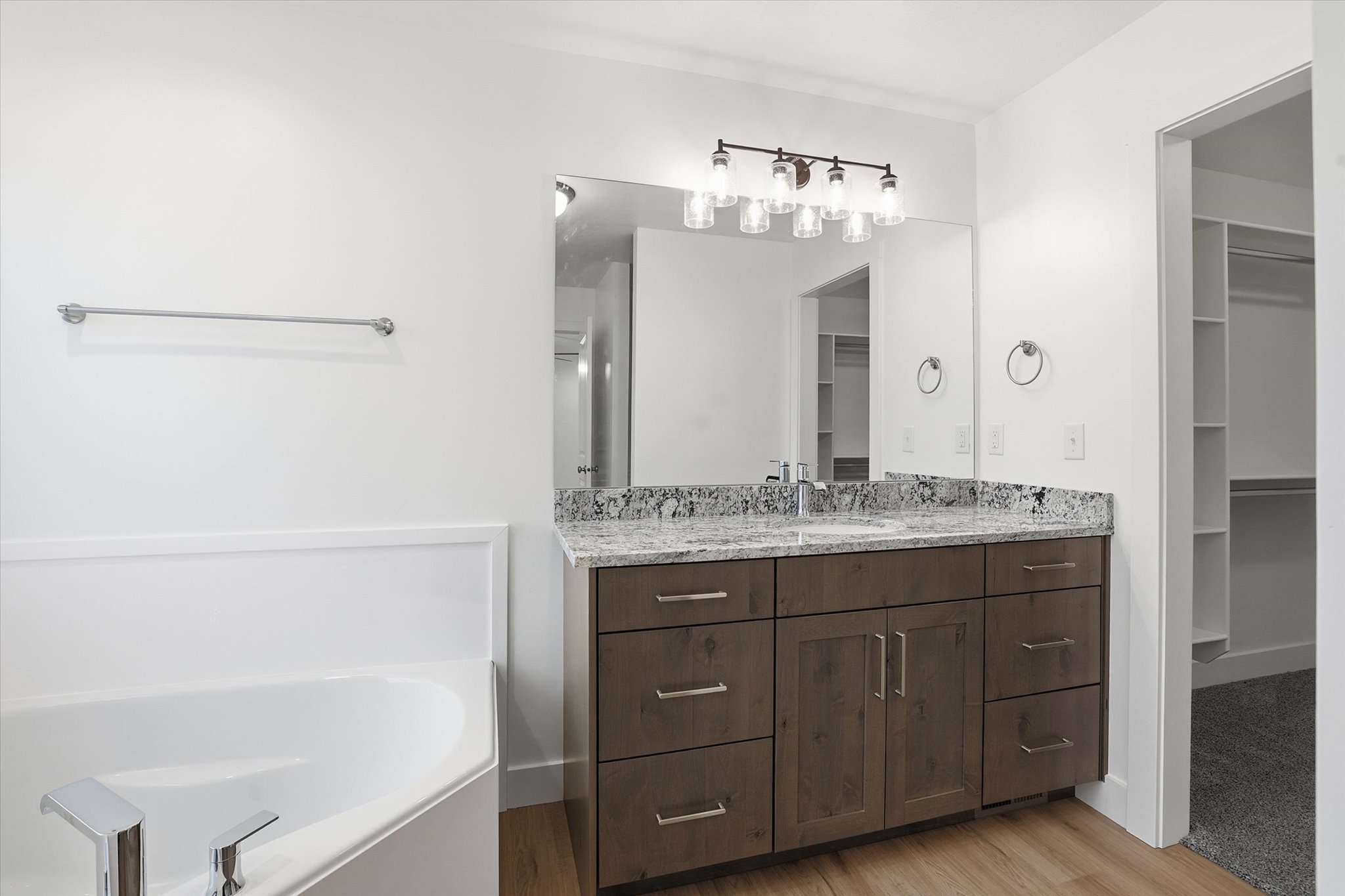 Bathroom vanity featuring a light-toned countertop, wood-finish cabinetry, and a large mirror