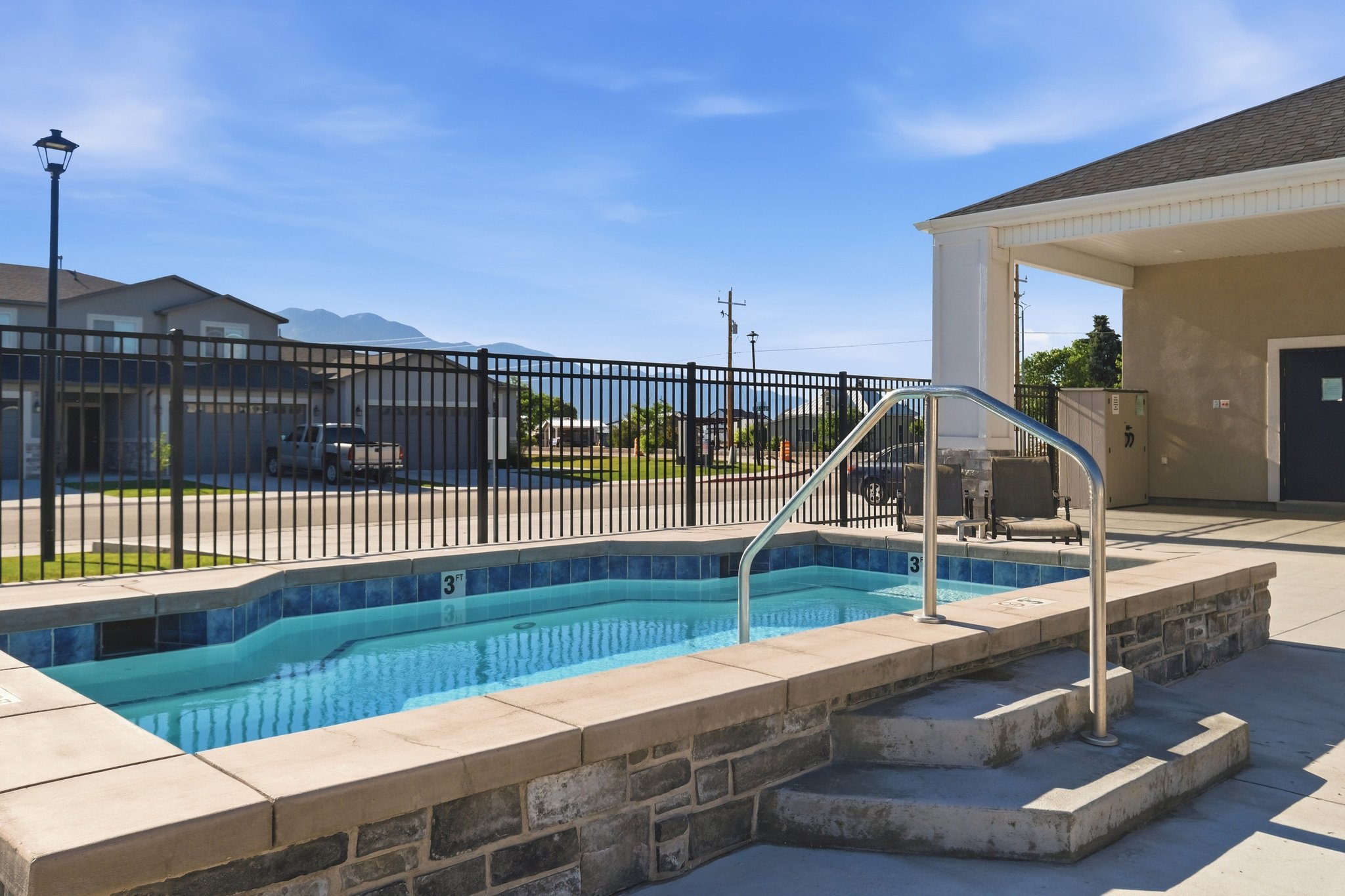 Outdoor spa featuring concrete steps, stainless steel handrail, and blue tiled interior