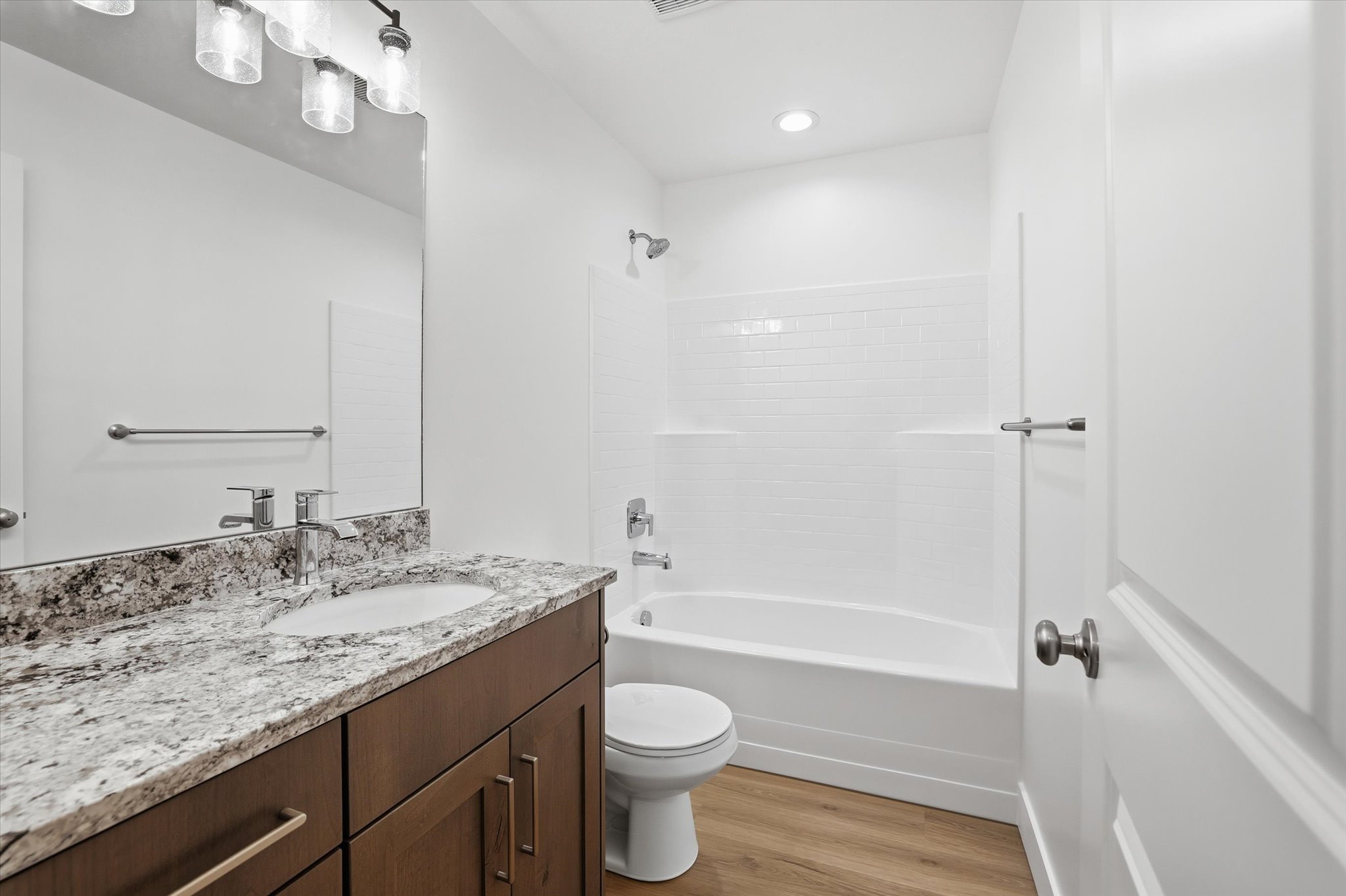 Bathroom featuring a single vanity with a granite-style countertop, undermount sink, and wood-finish cabinetry