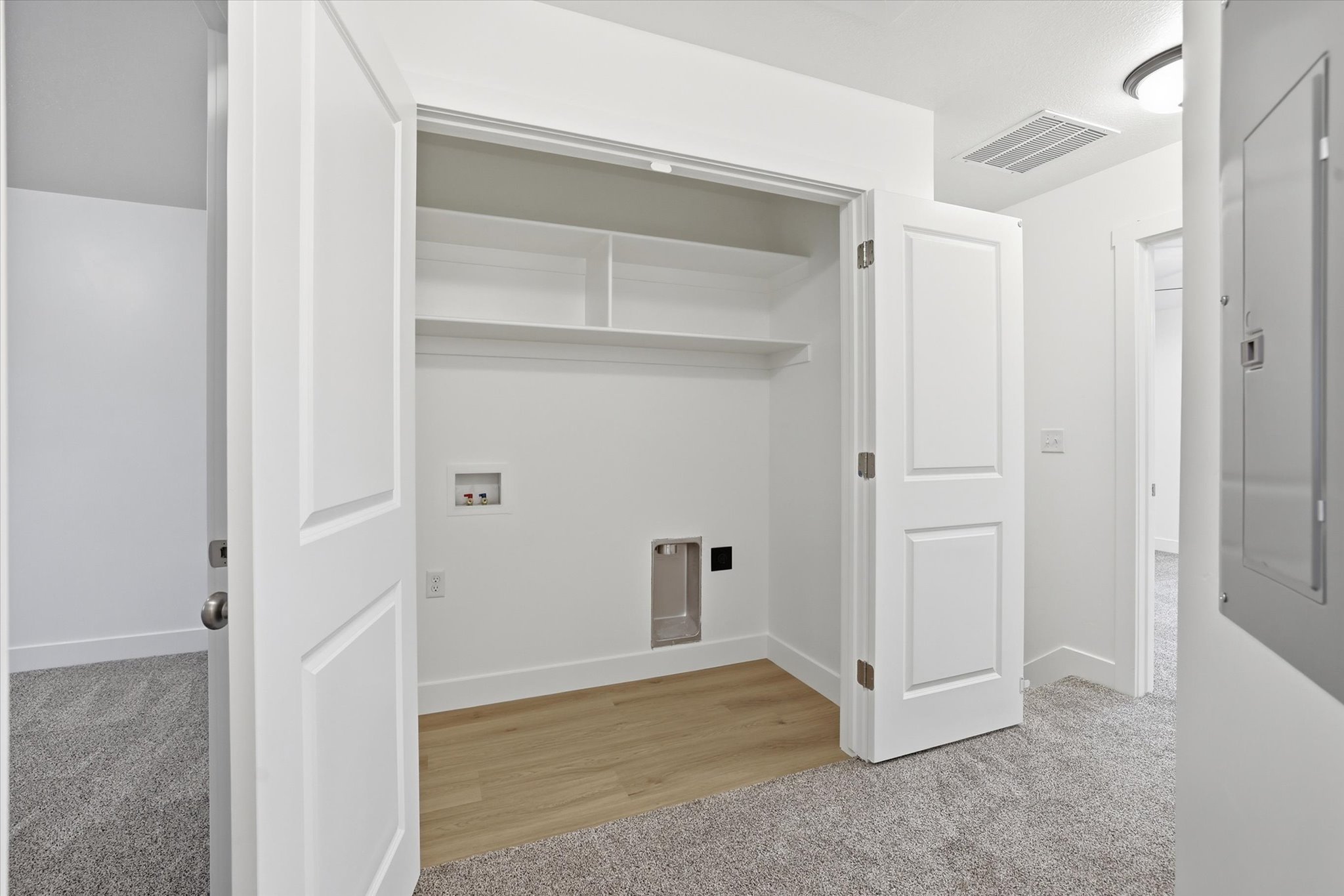 Dedicated laundry closet featuring wood-finish flooring, built-in shelving, and utility hookups