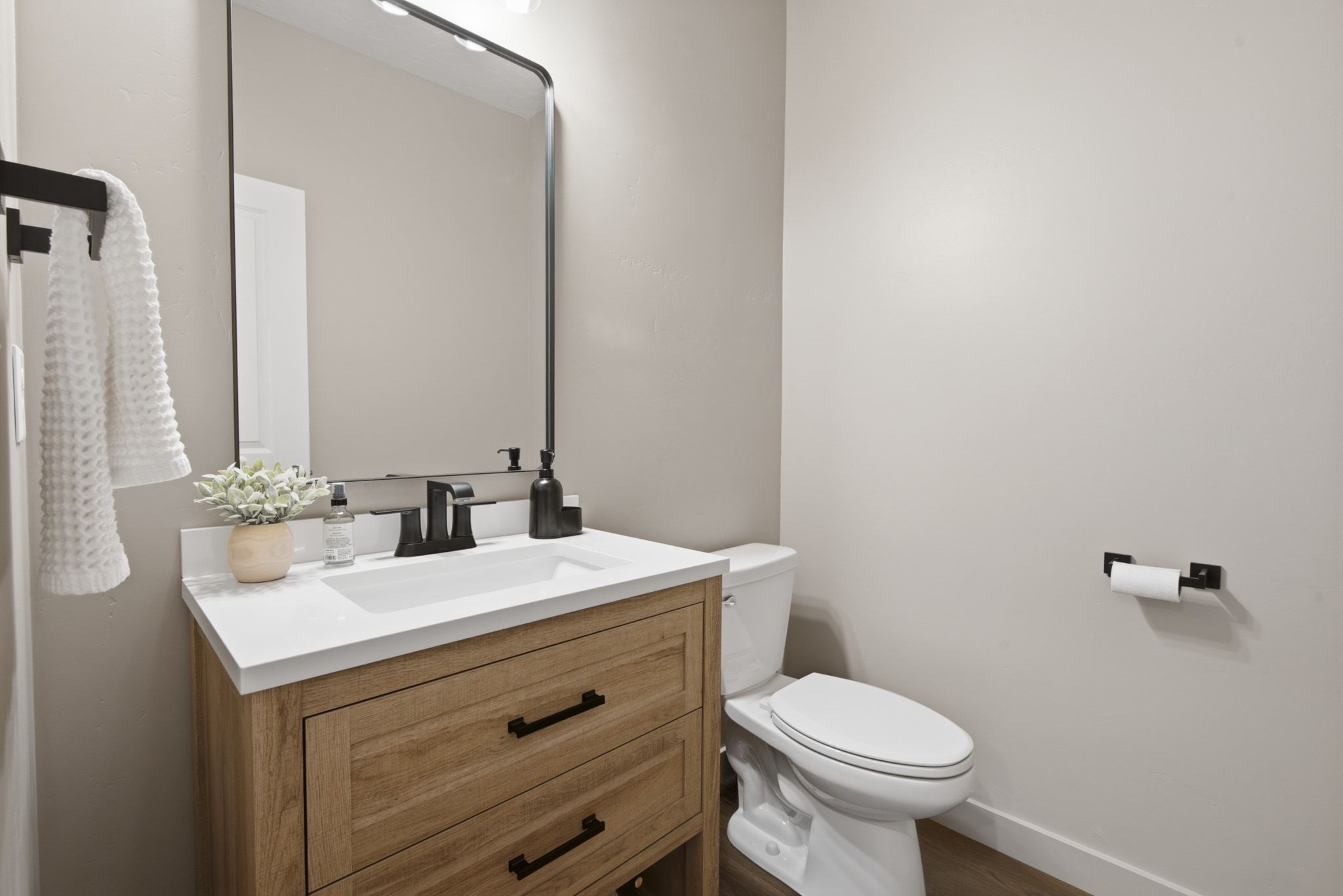 Vanity with wood-finish cabinetry, white countertop, and integrated sink