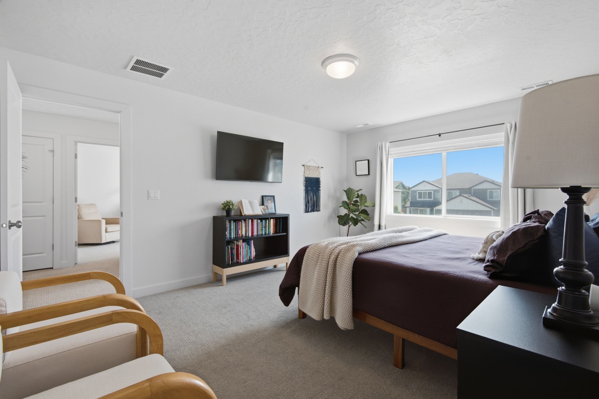 Bright room featuring a large window, neutral carpeting, and white walls