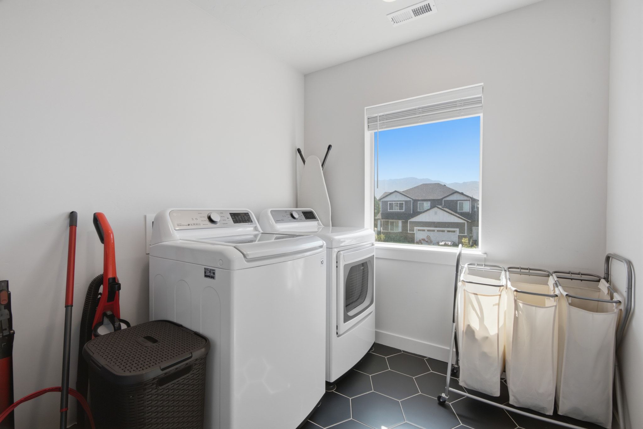 Laundry room featuring a large window, hexagonal tile flooring, and white walls