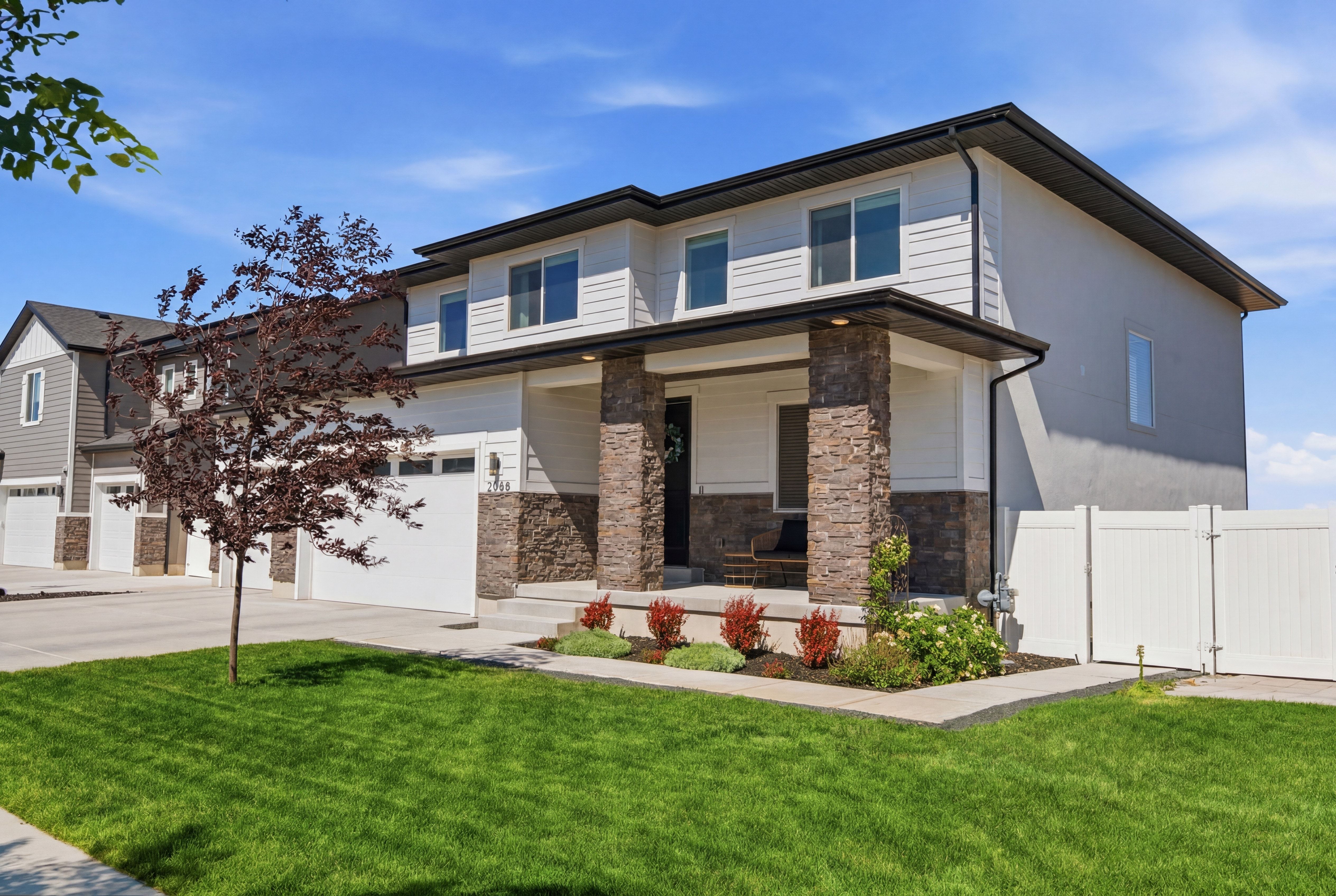 Contemporary two-story residence featuring a stone-clad porch with substantial pillars