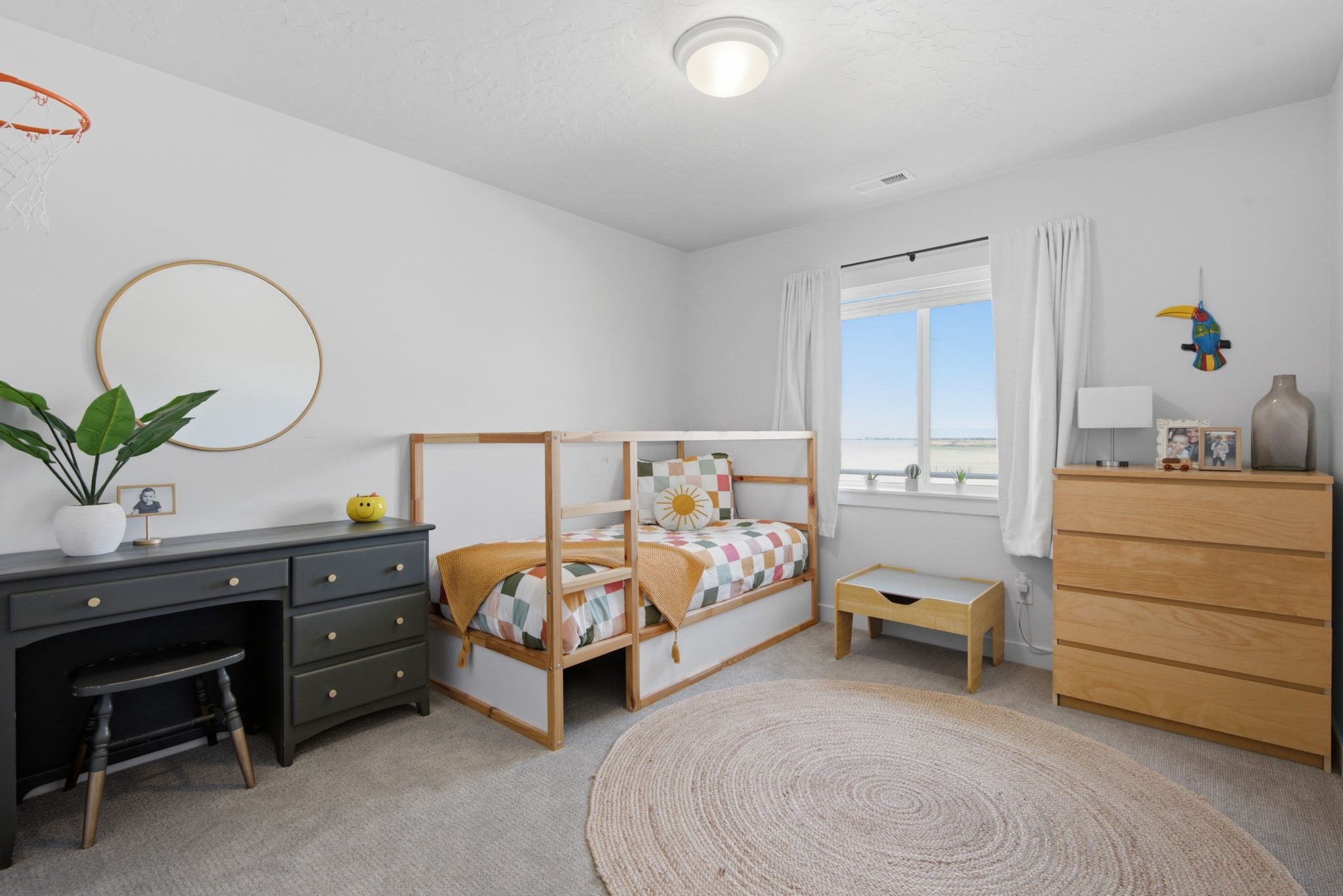 Bright room featuring a window with white curtains, light gray walls, and carpet flooring