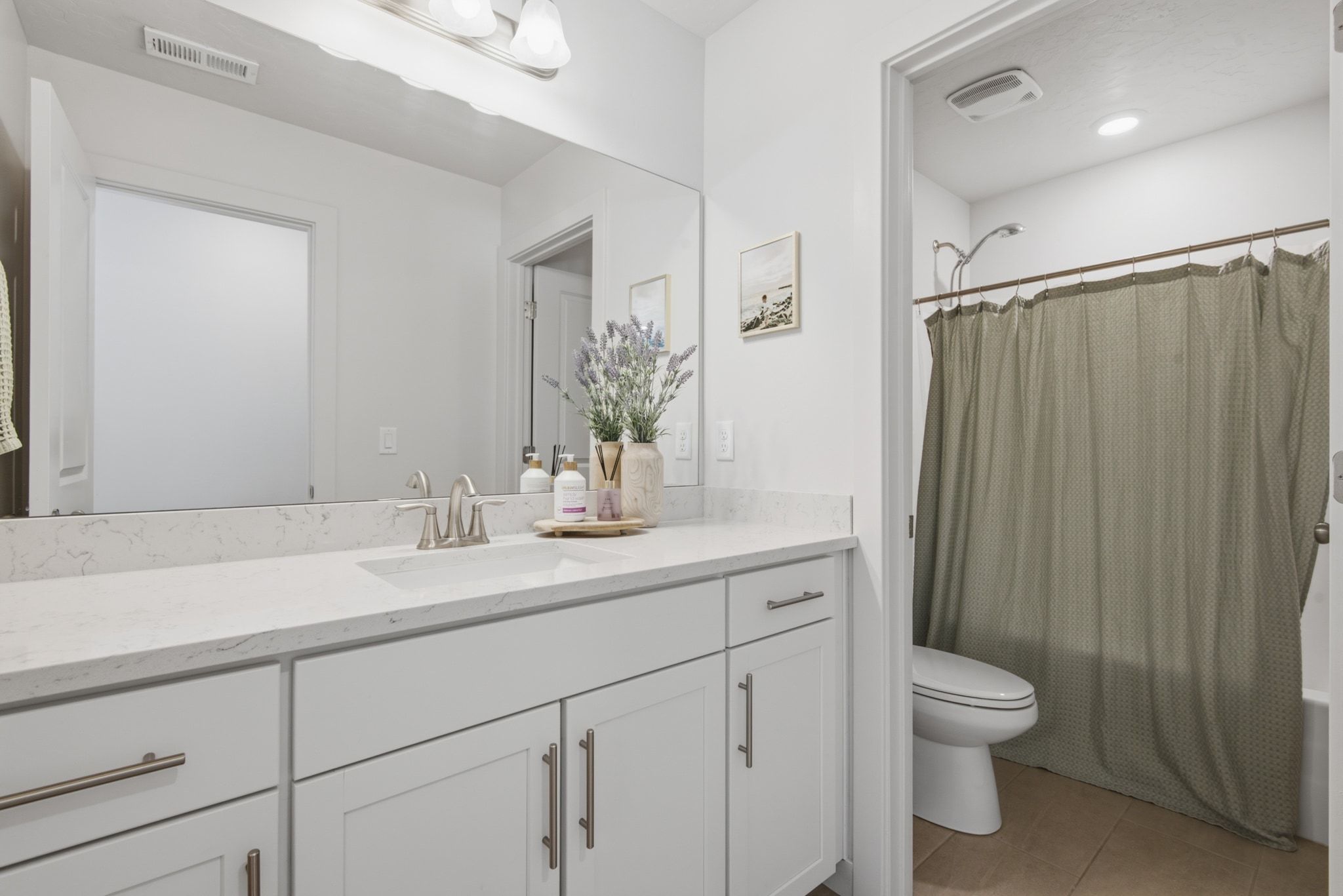 Bathroom featuring a white vanity with a light-toned countertop, undermount sink, and brushed nickel faucet