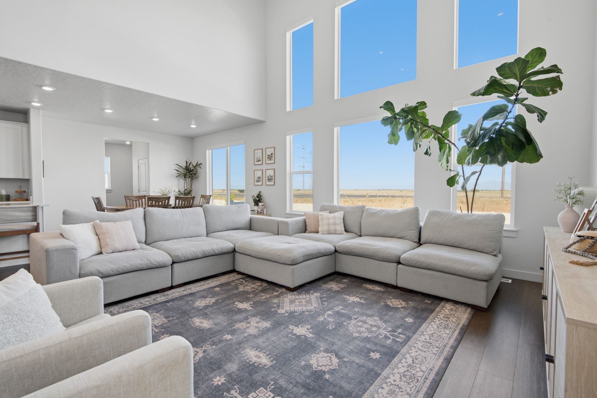 Double-height living space featuring expansive windows, wood-finish flooring, recessed lighting, and a neutral color palette